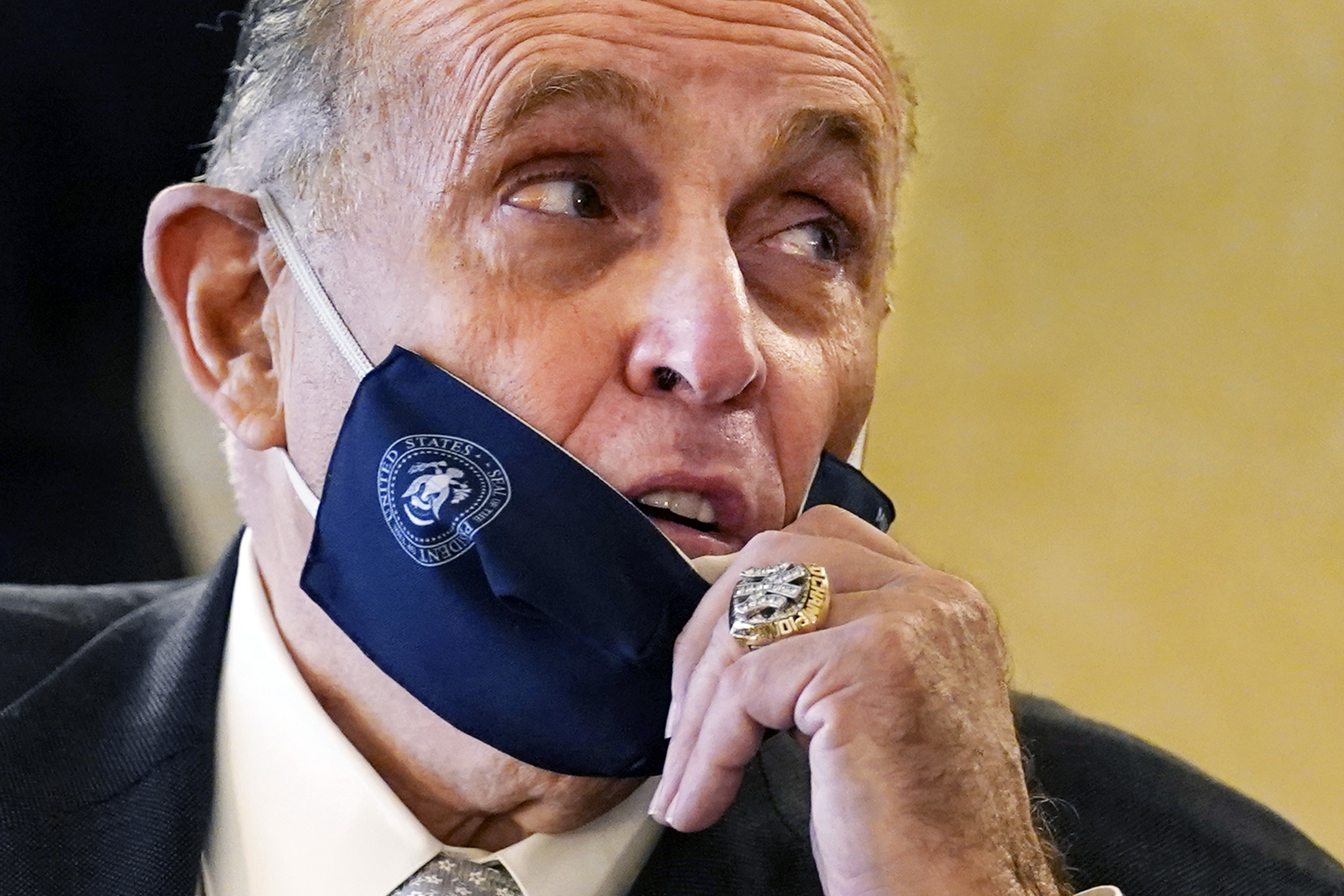 Former New York Mayor Rudy Giuliani, wearing a New York Yankees championship ring, pulls his face mask down to speak to an aide during a press conference at the Women's Republican Club in New York.