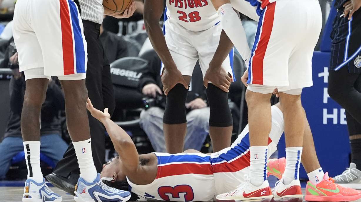 Teammates look over Detroit Pistons guard Jaden Ivey (23) after an incident during the second half of an NBA basketball game against the Orlando Magic, Wednesday, Jan. 1, 2025, in Detroit. Ivey was carted off the court by stretcher.
