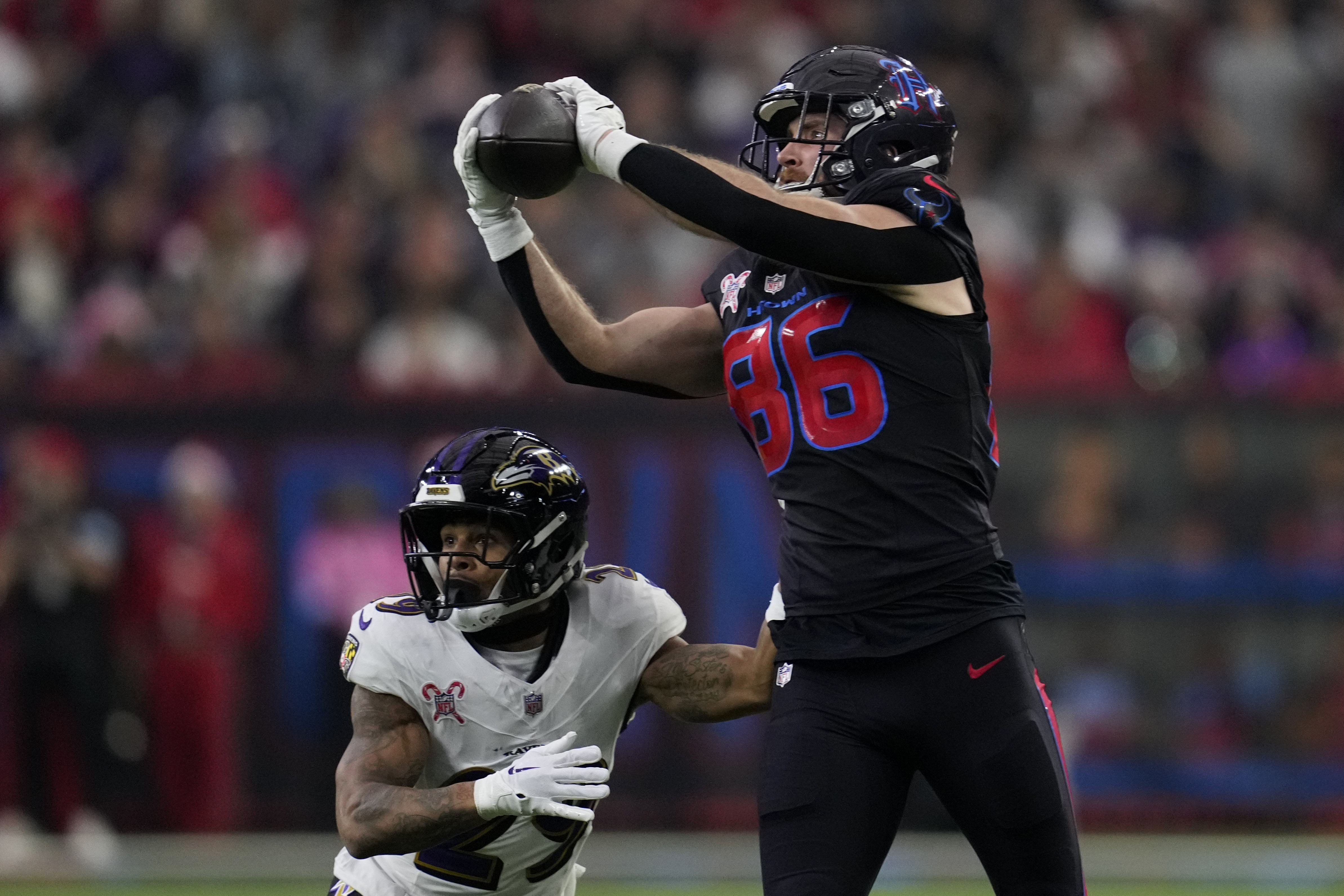 Houston Texans tight end Dalton Schultz (86) catches a pass over Baltimore Ravens safety Ar'Darius Washington (29) during the first half of an NFL football game, Wednesday, Dec. 25, 2024, in Houston.