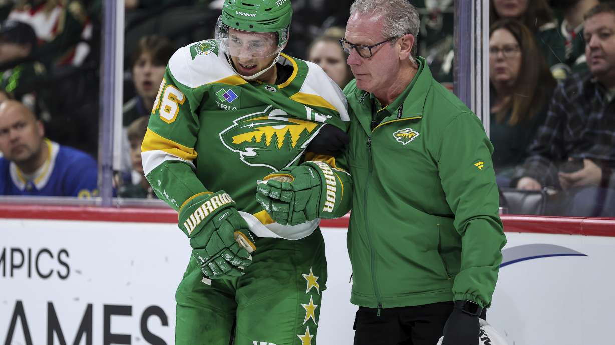 Minnesota Wild athletic trainer John Worley, right, helps defenseman Jared Spurgeon off the ice after an injury during the second period of an NHL hockey game against the Nashville Predators Tuesday, Dec. 31, 2024, in St. Paul, Minn.
