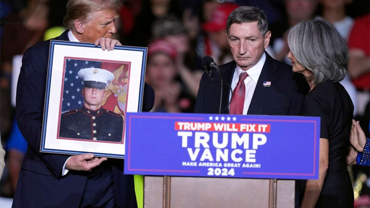 President-elect Donald Trump holds a photo of Marine veteran Nicholas Douglas Quets, who was allegedly killed in Mexico by cartel members, as his parents, retired Army Lt. Col. Warren Douglas Quets and Patricia, speak during a campaign rally.