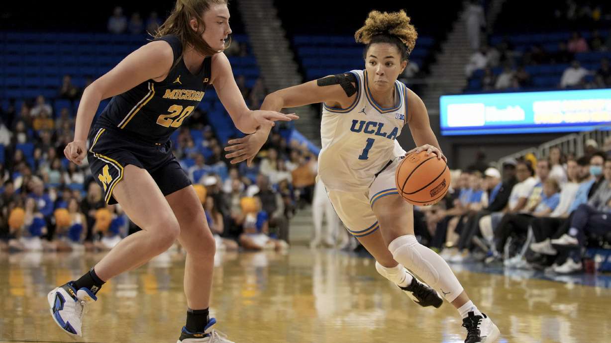 UCLA guard Kiki Rice (1) dribbles around Michigan forward Alyssa Crockett (20) during the first half of an NCAA college basketball game in Los Angeles, Wednesday, Jan. 1, 2025.