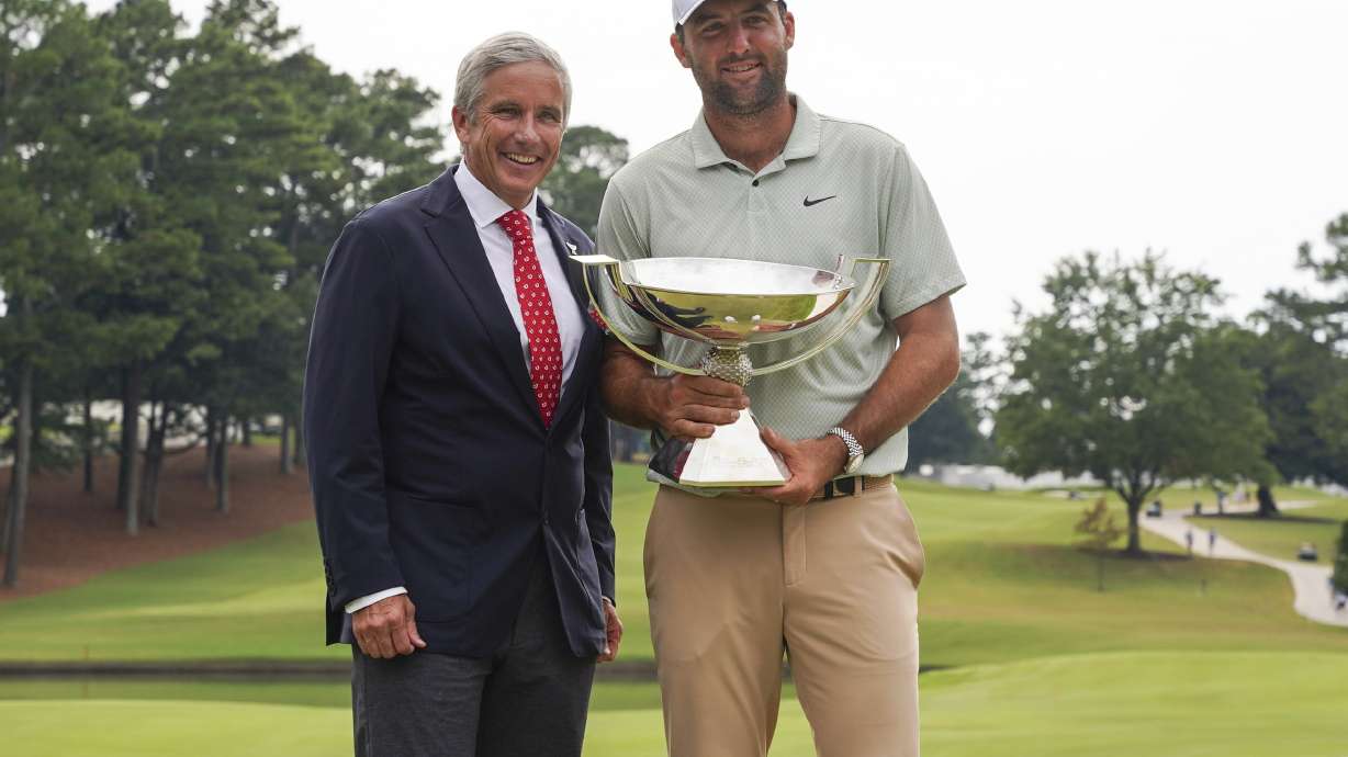 FILE - PGA Tour Commissioner Jay Monahan, left, poses with Scottie Scheffler and the FedExCup Trophy after Scheffler won the final round of the Tour Championship golf tournament, Sunday, Sept. 1, 2024, in Atlanta.