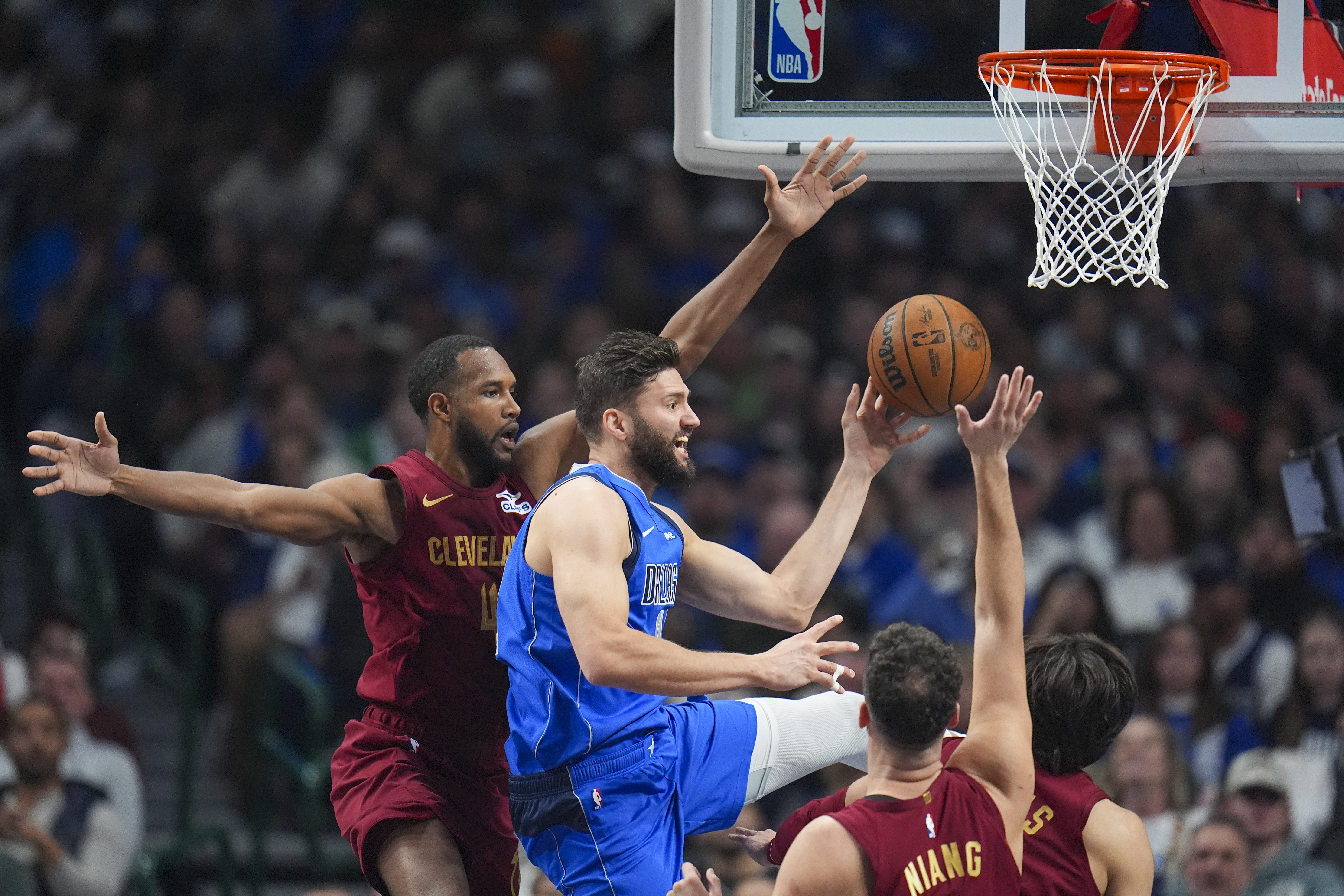 Dallas Mavericks forward Maxi Kleber, center, makes a pass as Cleveland Cavaliers forward Evan Mobley, left, and teammates defend during the first half of an NBA basketball game, Friday, Jan. 3, 2025, in Dallas.