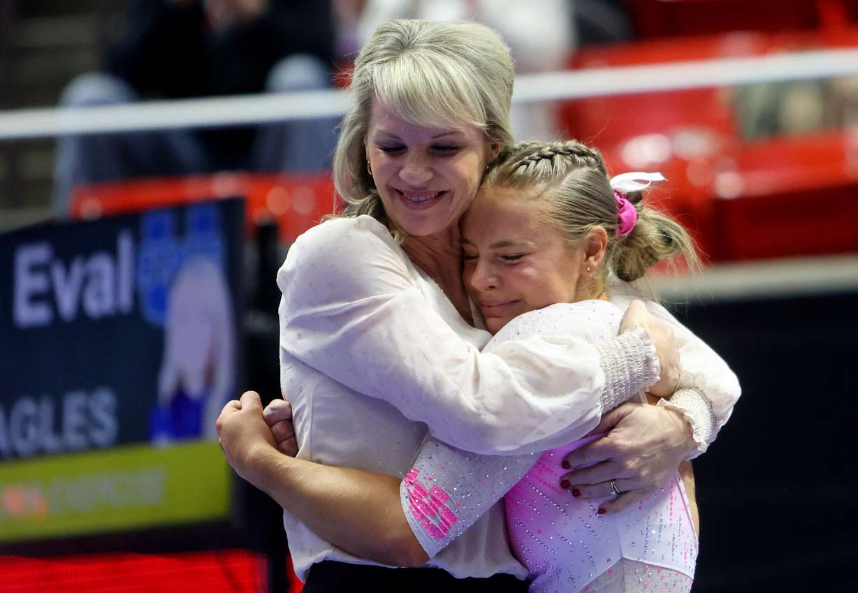 Utah Red Rocks’ head coach Carly Dockendorf hugs Utah Red Rocks’ Camie Winger as they react to Winger’s score of 9.950 on the beam during a gymnastics meet against Utah State University at the Huntsman Center in Salt Lake City on Friday, Jan. 3, 2025. The University of Utah won.