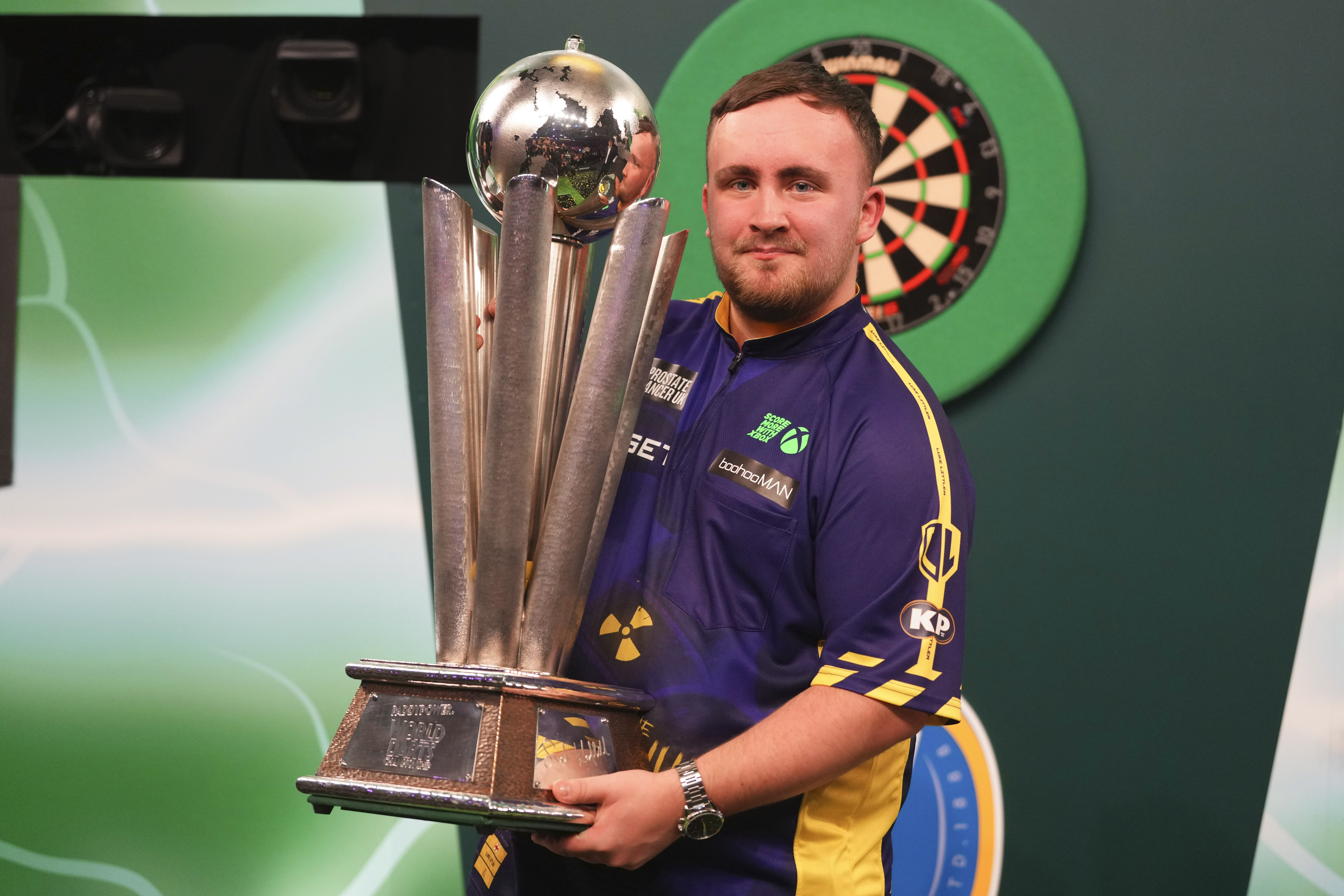 Luke Littler of England holds the trophy after winning the final against Michael van Gerwen of the Netherlands at the World Darts Championship at Alexandra Palace in London, Friday, Jan. 3, 2025.