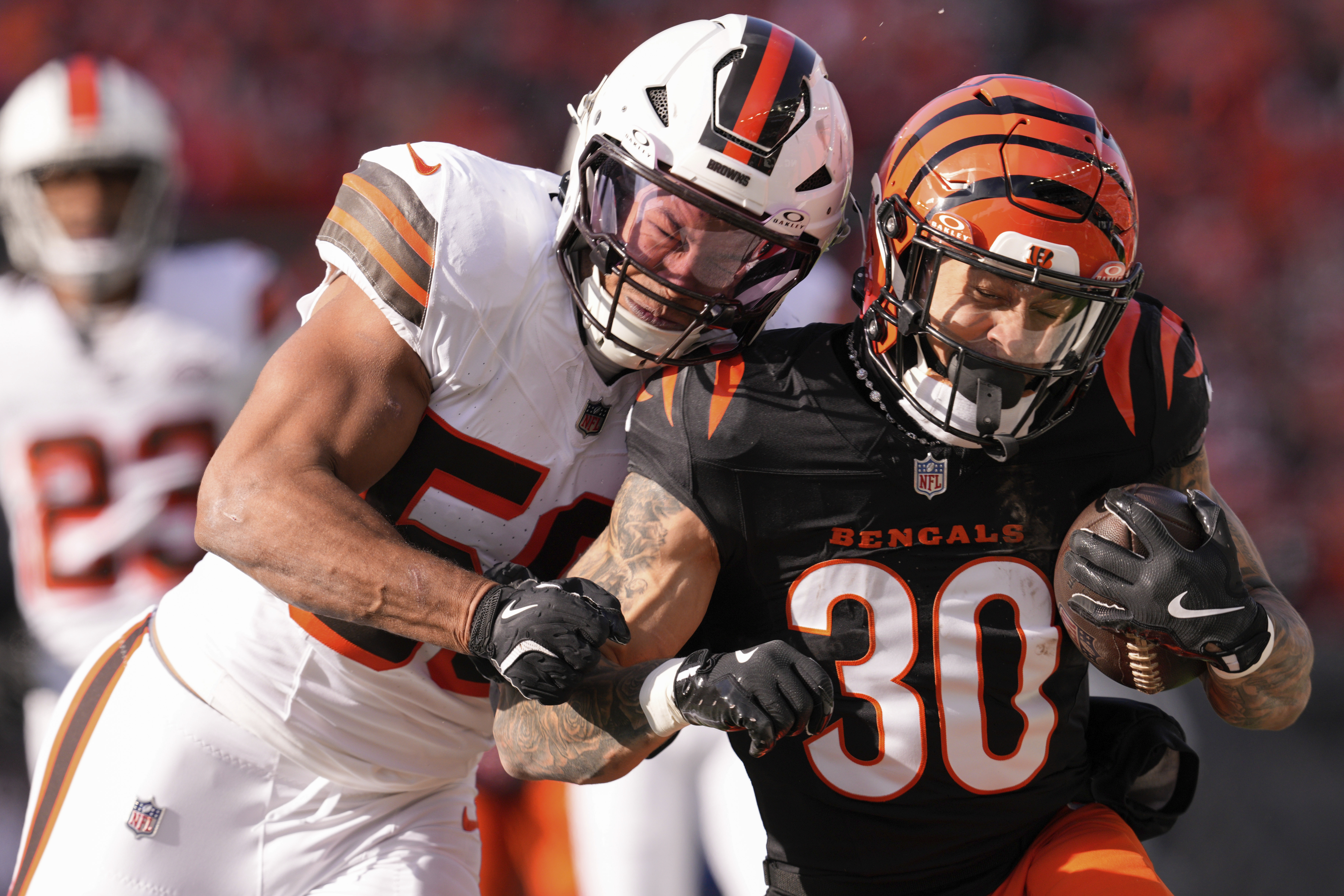 Cincinnati Bengals running back Chase Brown (30) runs the ball as Cleveland Browns linebacker Jordan Hicks, left, defends during the first half of an NFL football game against the Cleveland Browns, Sunday, Dec. 22, 2024, in Cincinnati.