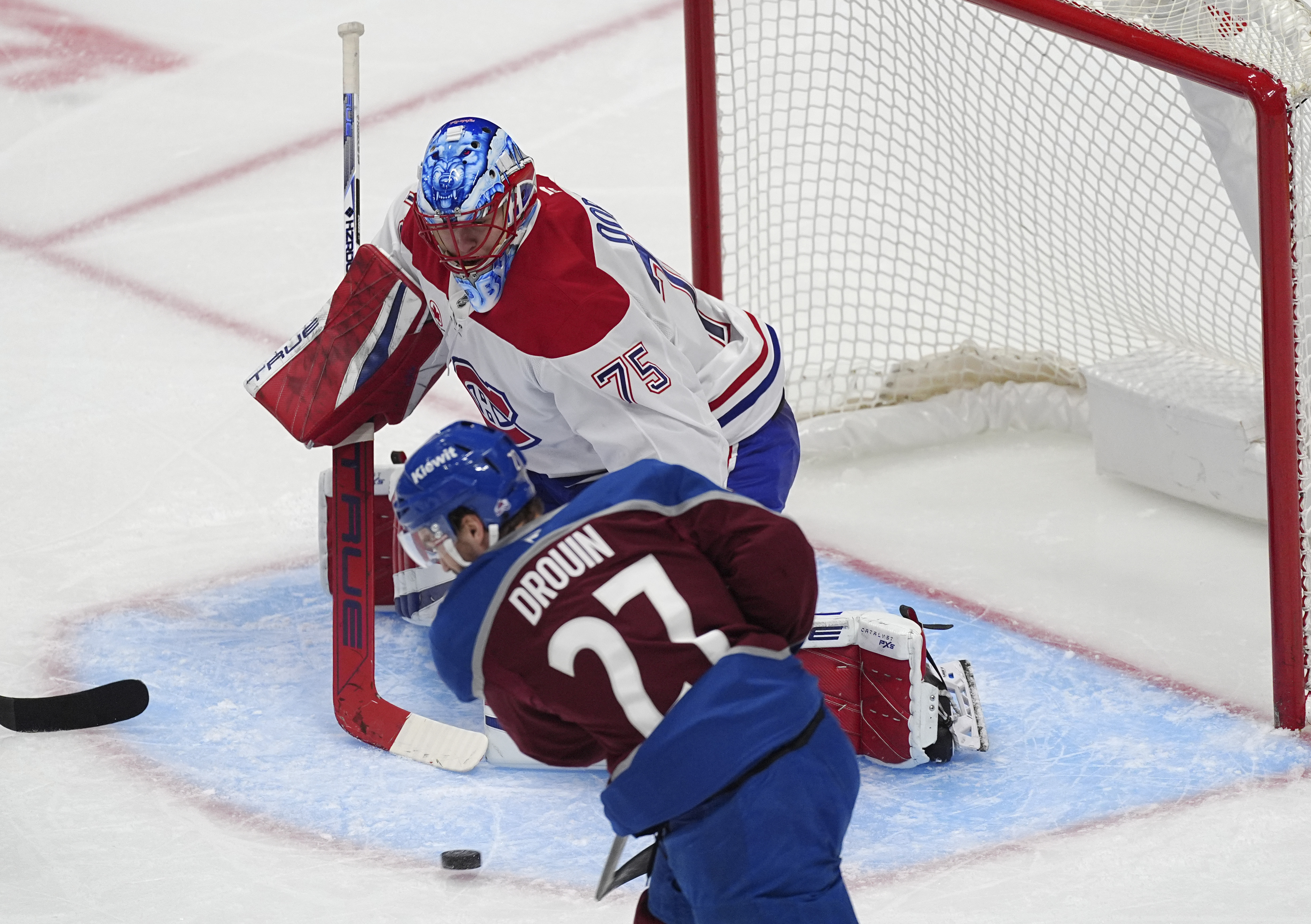 Colorado Avalanche left wing Jonathan Drouin, front, puts a shot on Montreal Canadiens goaltender Jakub Dobes in the second period of an NHL hockey game Saturday, Jan. 4, 2025, in Denver.