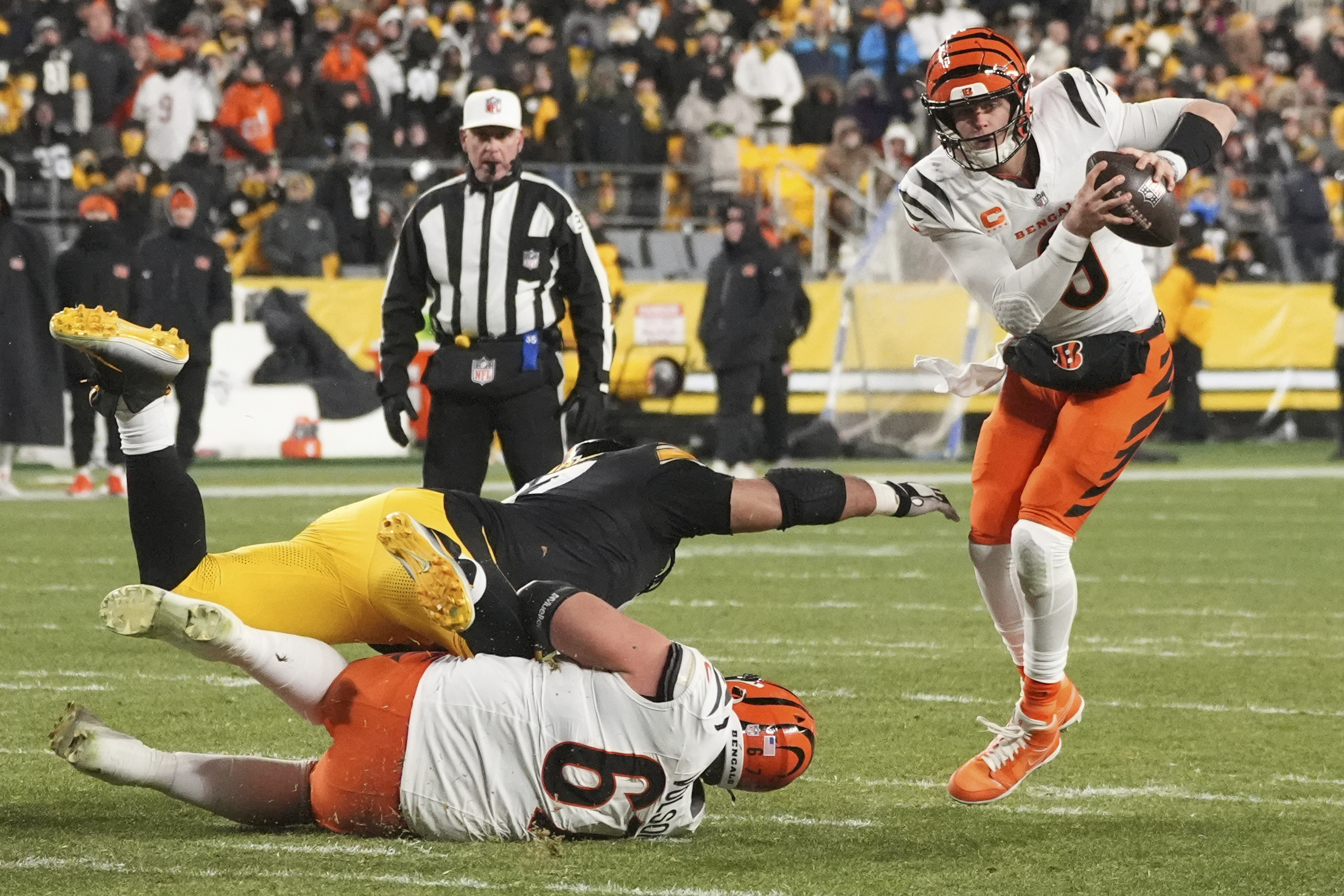 Cincinnati Bengals quarterback Joe Burrow (9) avoids Pittsburgh Steelers defensive tackle Cameron Heyward (97) with Cincinnati Bengals guard Cordell Volson (67) during the second half of an NFL football game in Pittsburgh, Saturday, Jan. 4, 2025.