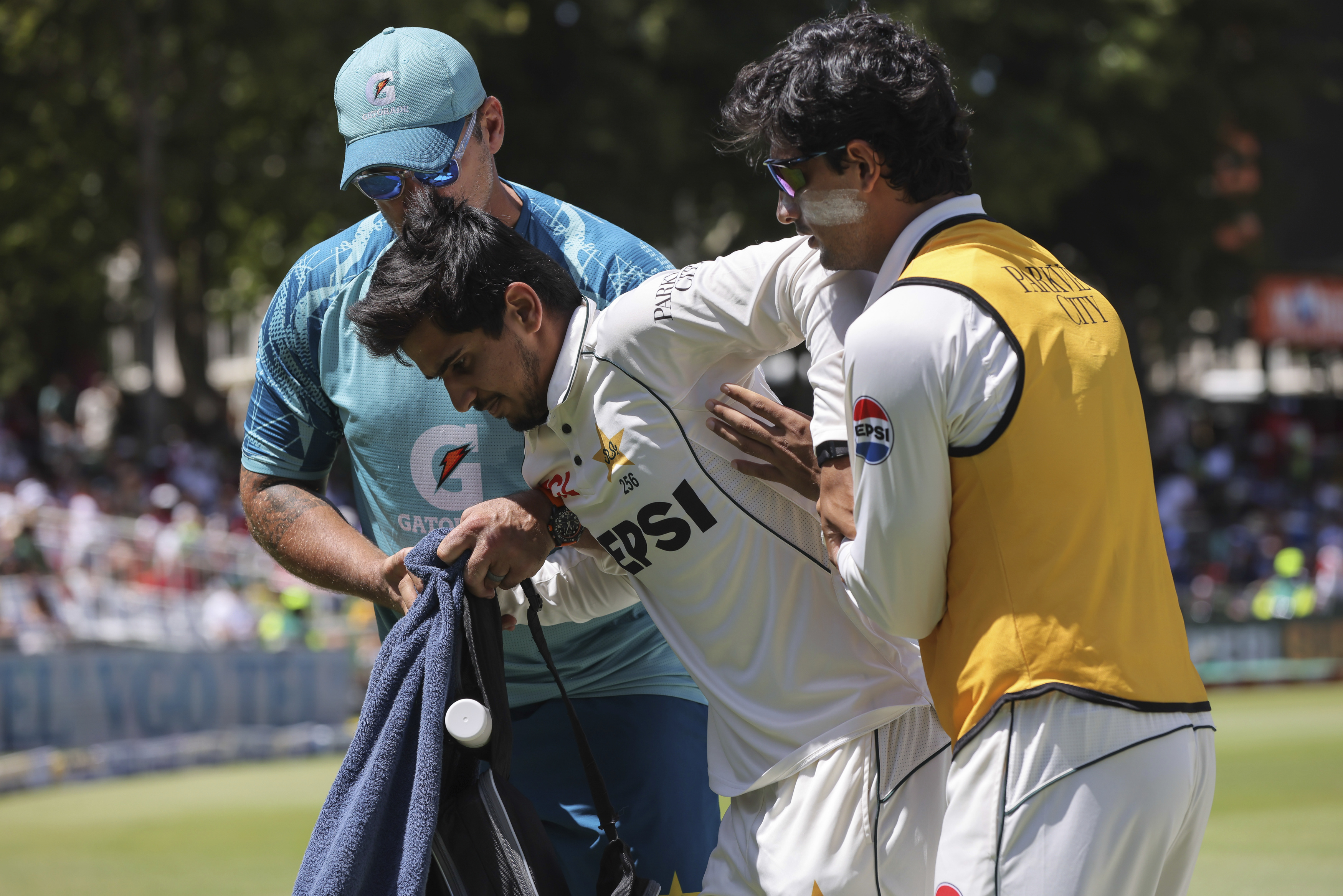 Pakistan's Saim Ayub is helped from the field after injuring his ankle while fielding the ball during the second test match between South Africa and Pakistan in Cape Town, South Africa, Friday, Jan. 3, 2025.