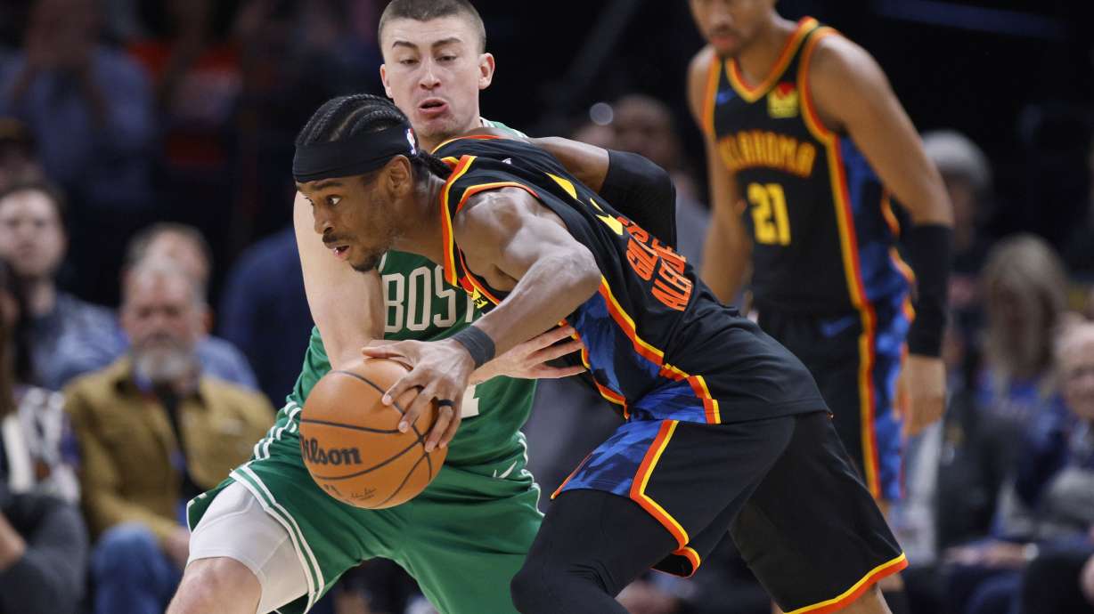 Oklahoma City Thunder guard Shai Gilgeous-Alexander, front, drives against Boston Celtics guard Payton Pritchard, back, during the first half of an NBA basketball game Sunday, Jan. 5, 2025, in Oklahoma City.