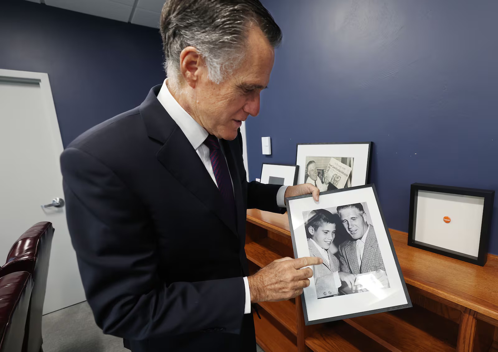 Sen. Mitt Romney, R-Utah, holds a photo of himself and his father George Romney in his office in Salt Lake City on Dec. 13, 2024.