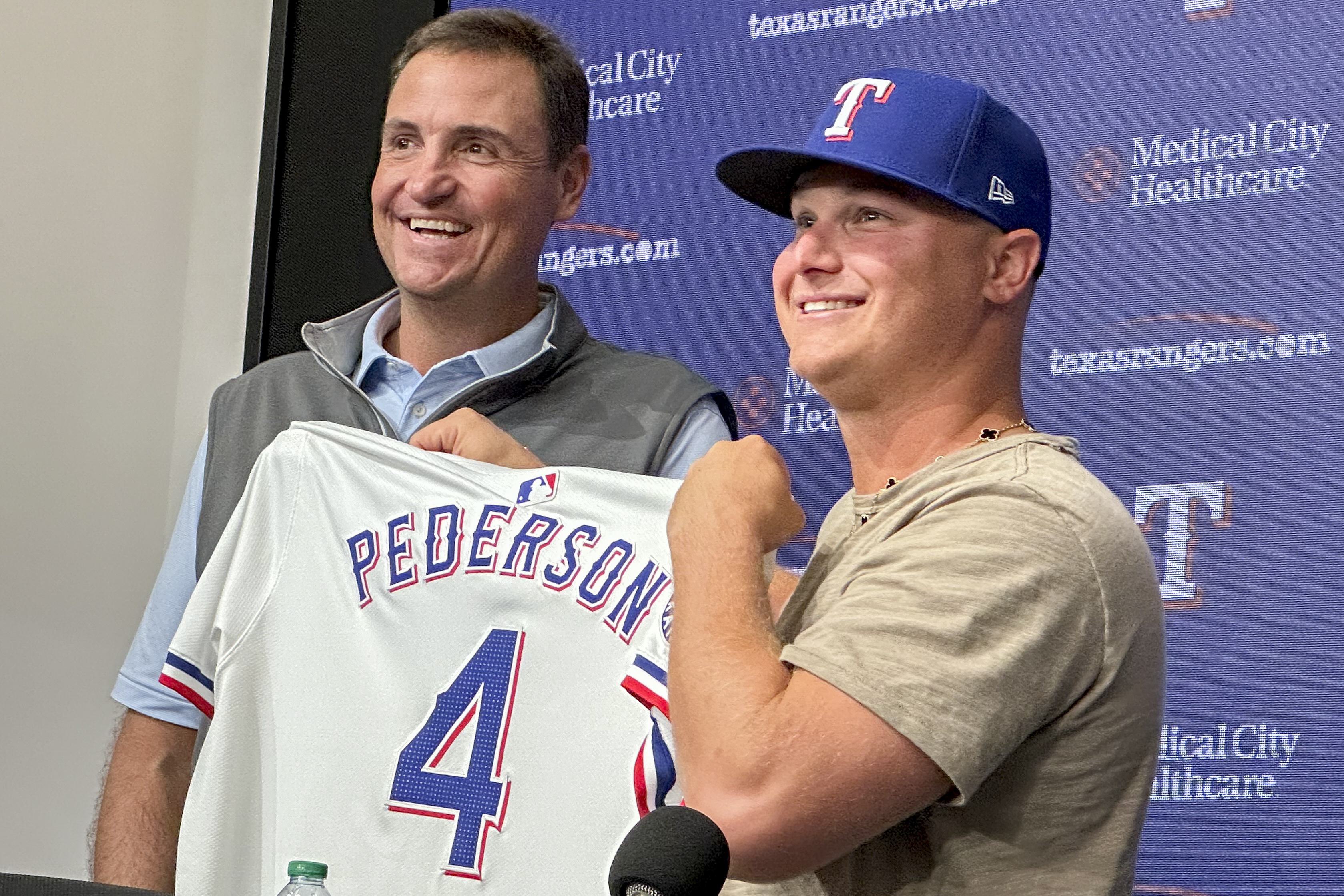 Texas Rangers president of baseball operations Chris Young, left, poses for photos with Joc Pederson during a news conference announcing Pederson's two-year contract with the team, Monday, Dec. 30, 2024, in Arlington, Texas.