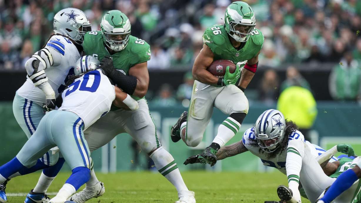 Philadelphia Eagles running back Saquon Barkley, center, leaps as Dallas Cowboys linebacker Marist Liufau tries to trip him up during the second half of an NFL football game, Sunday, Dec. 29, 2024, in Philadelphia.