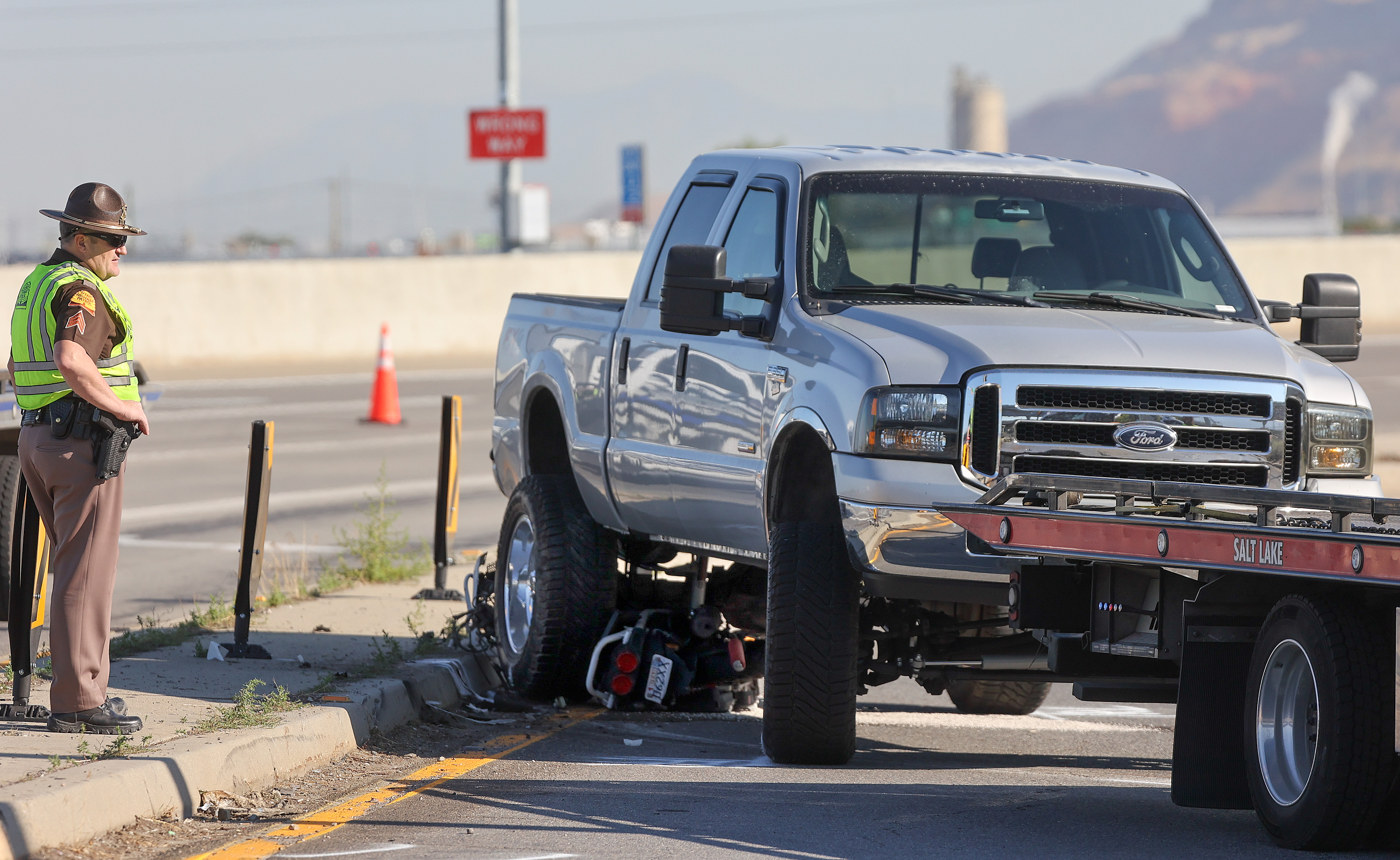 A Utah Highway Patrol trooper looks at a motorcycle underneath a truck at the scene of an accident near the I-15 exit ramp and 2100 South in Salt Lake City on Aug. 26, 2024. Preliminary Utah data shows 281 people died on Utah roads last year.