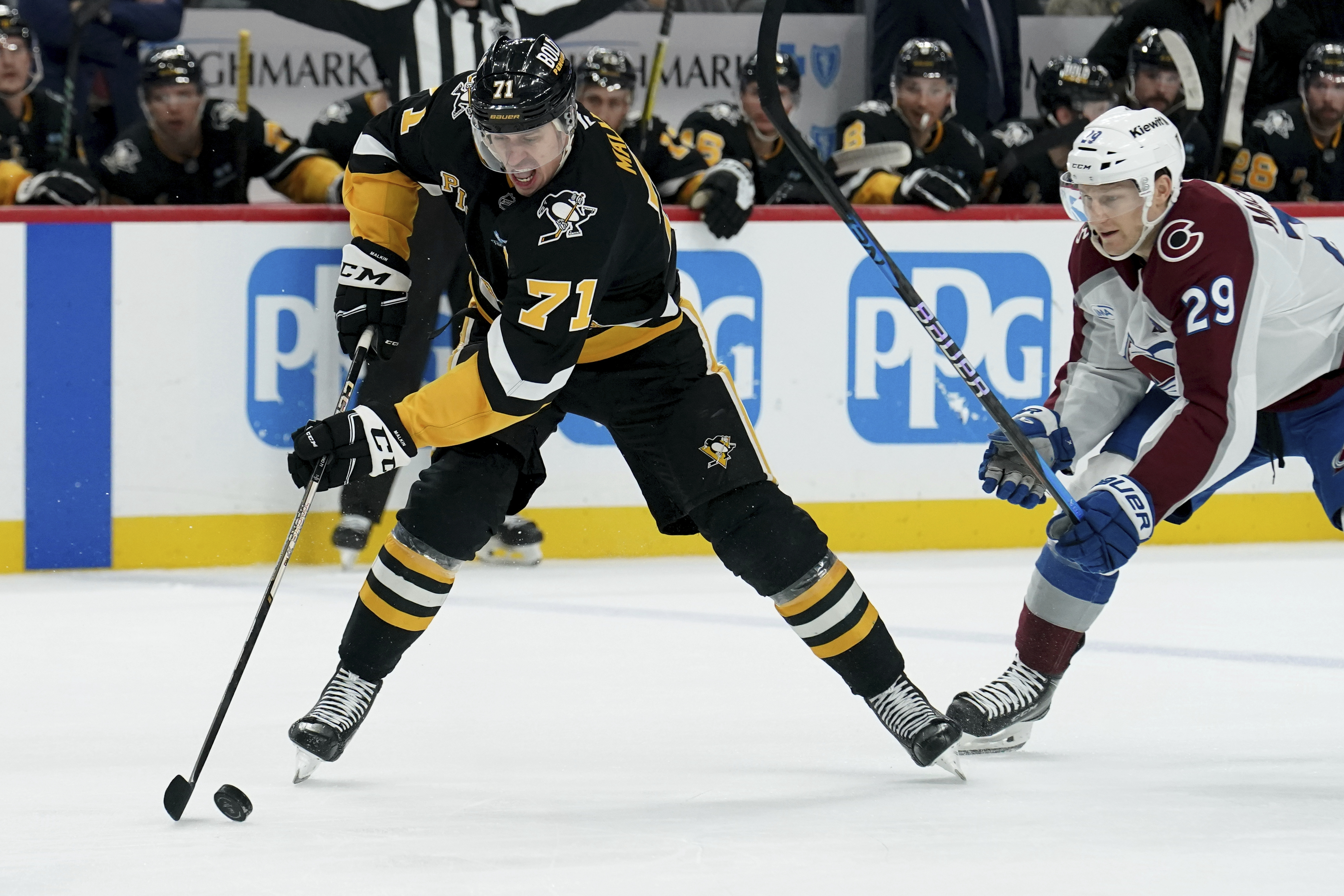 Pittsburgh Penguins' Evgeni Malkin (71) reaches for the puck against Colorado Avalanche's Nathan MacKinnon (29) during the second period of an NHL hockey game Tuesday, Dec. 10, 2024, in Pittsburgh.
