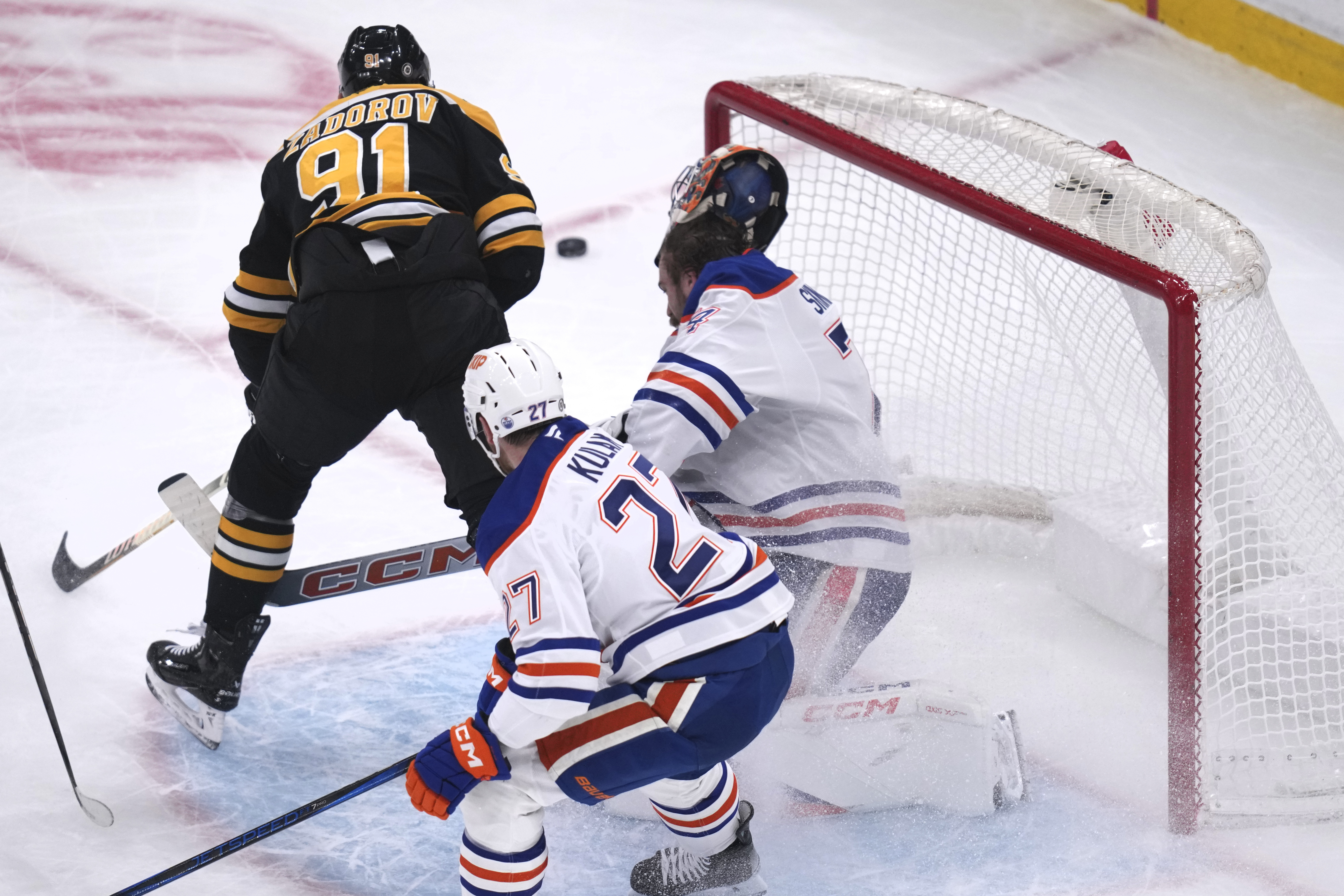 Edmonton Oilers goaltender Stuart Skinner, right, falls back after a collision with Boston Bruins defenseman Nikita Zadorov (91) during the first period of an NHL hockey game, Tuesday, Jan. 7, 2025, in Boston.