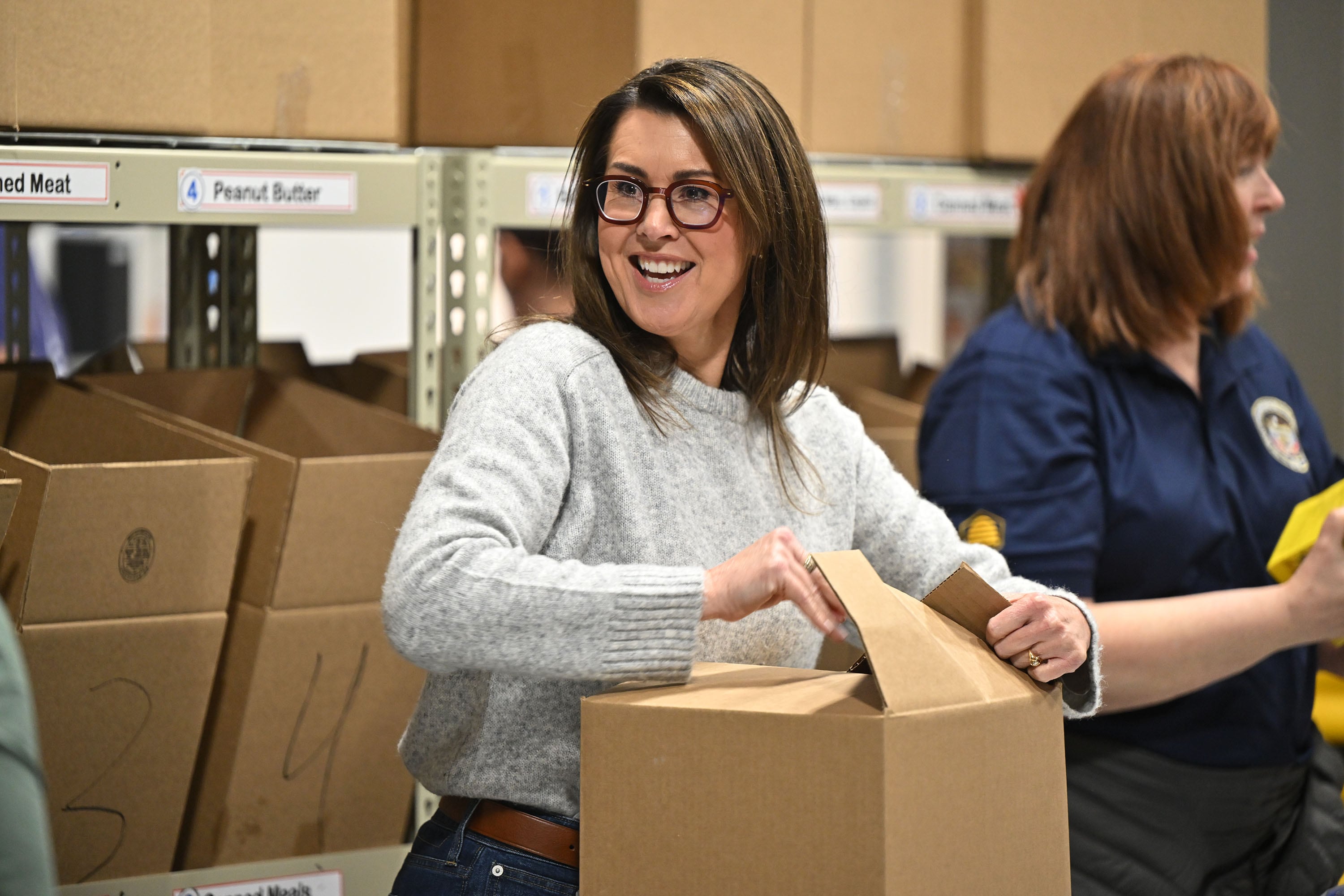 Utah Lt. Gov. Deidre Henderson, closes up a box of food as she, Gov. Spencer Cox and first lady Abby Cox and other government workers and staff join together at the Utah Food Bank to serve in Salt Lake City on Tuesday.