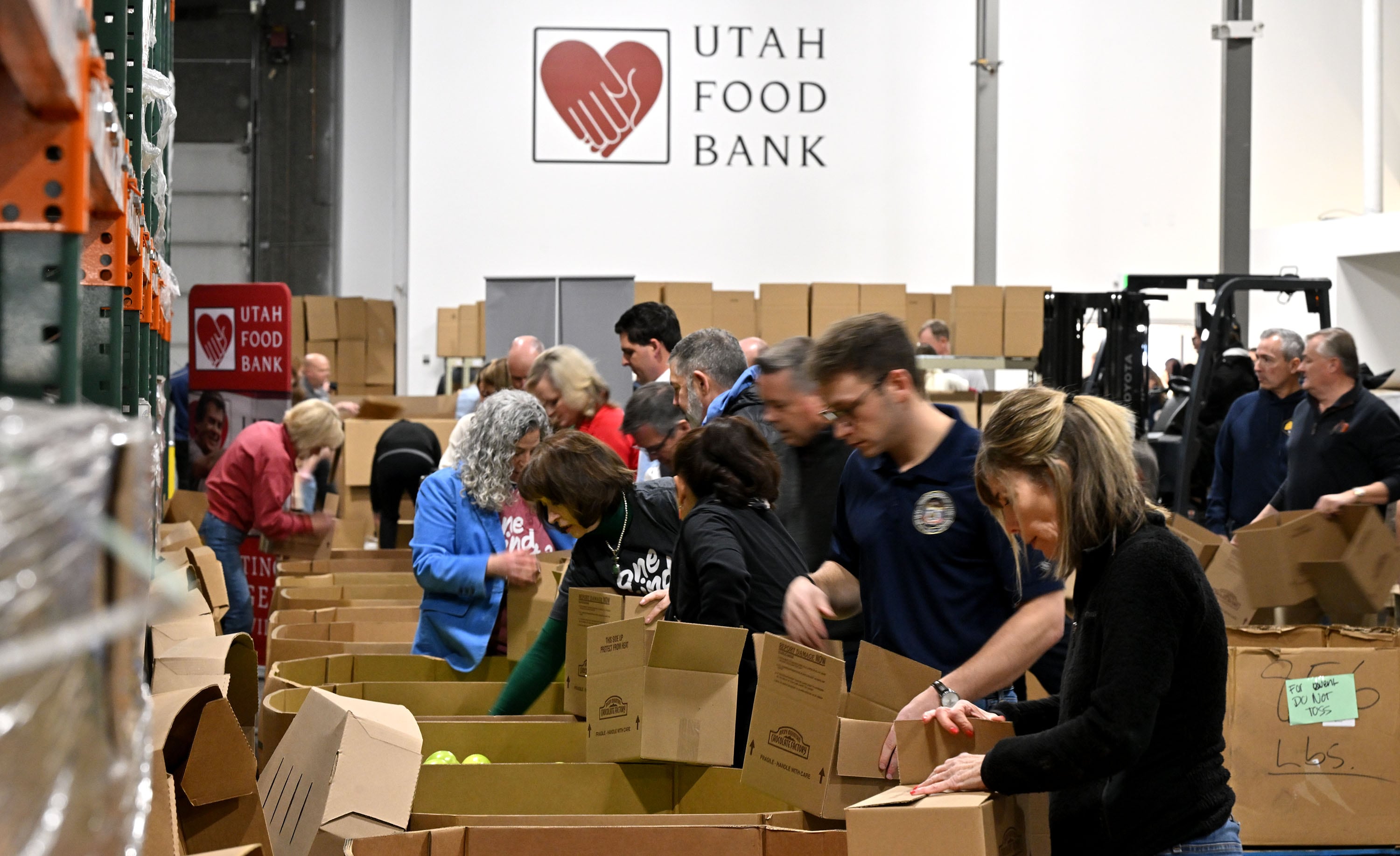 State employees and officials sort apples and other food items along with Gov. Spencer Cox and first lady Abby Cox at the Utah Food Bank to serve in Salt Lake City on Tuesday.