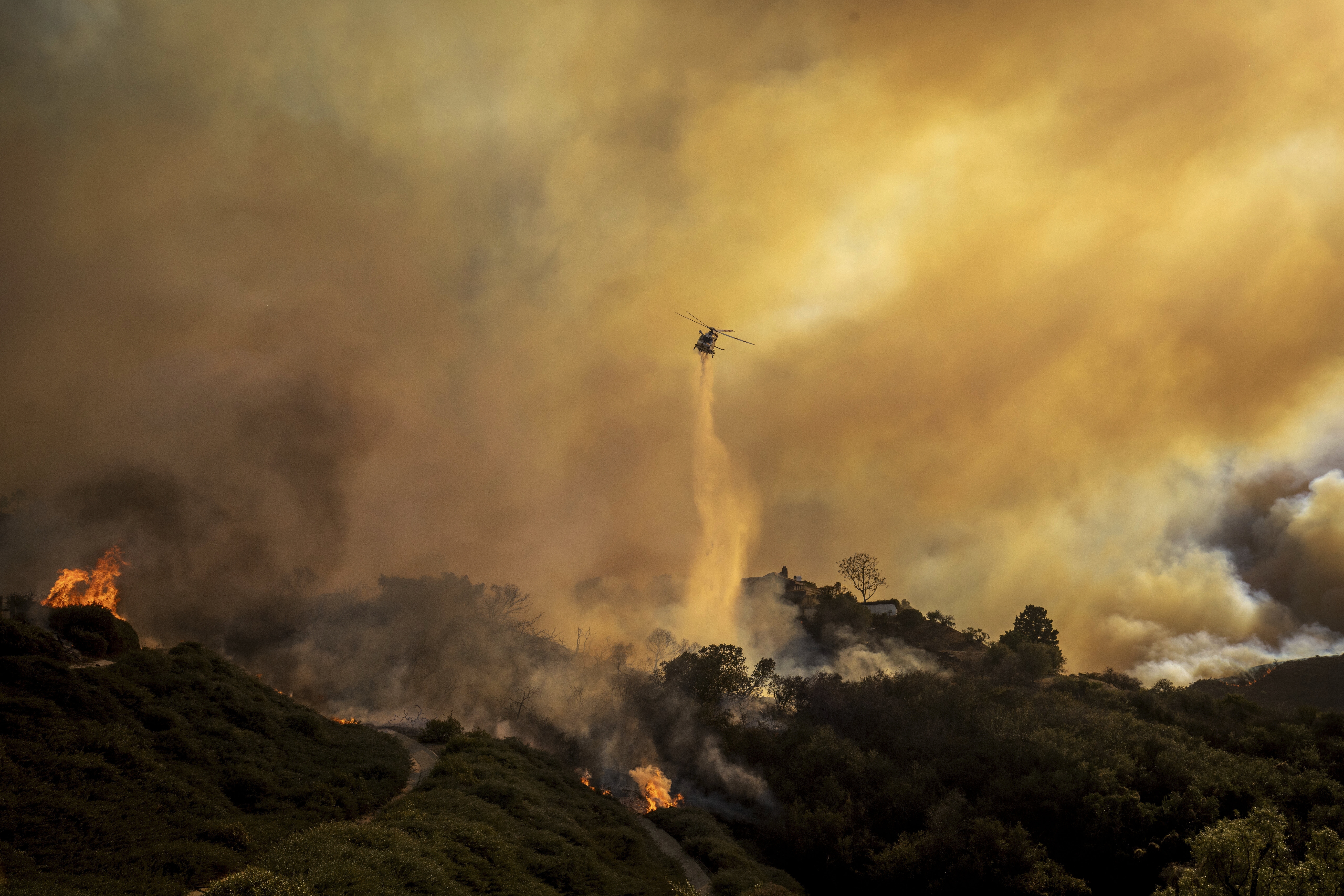 Water is dropped on the advancing Palisades Fire by helicopter in the Pacific Palisades neighborhood of Los Angeles, Tuesday.