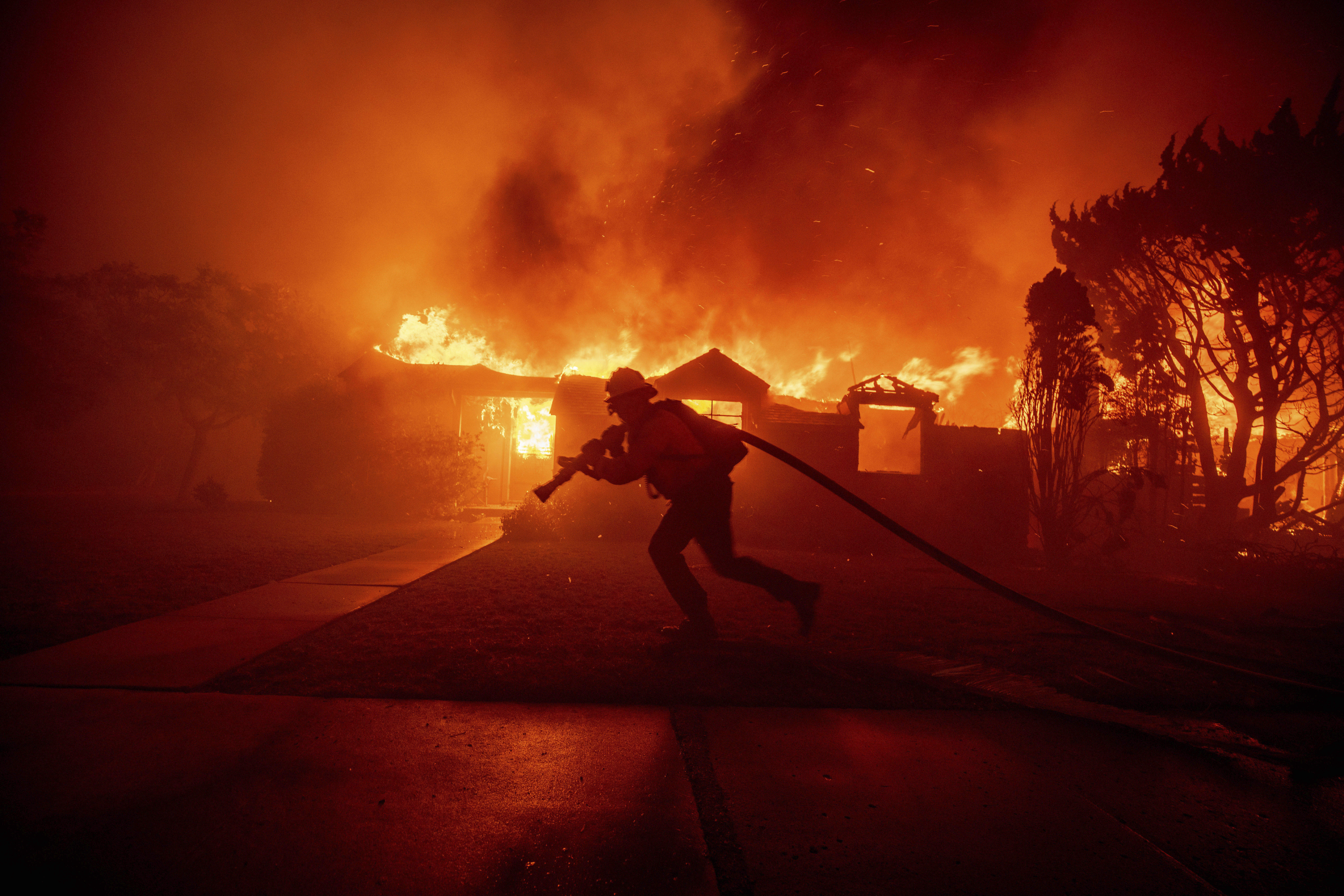 A firefighter battles the Palisades Fire as it burns a structure in the Pacific Palisades neighborhood of Los Angeles, Tuesday.
