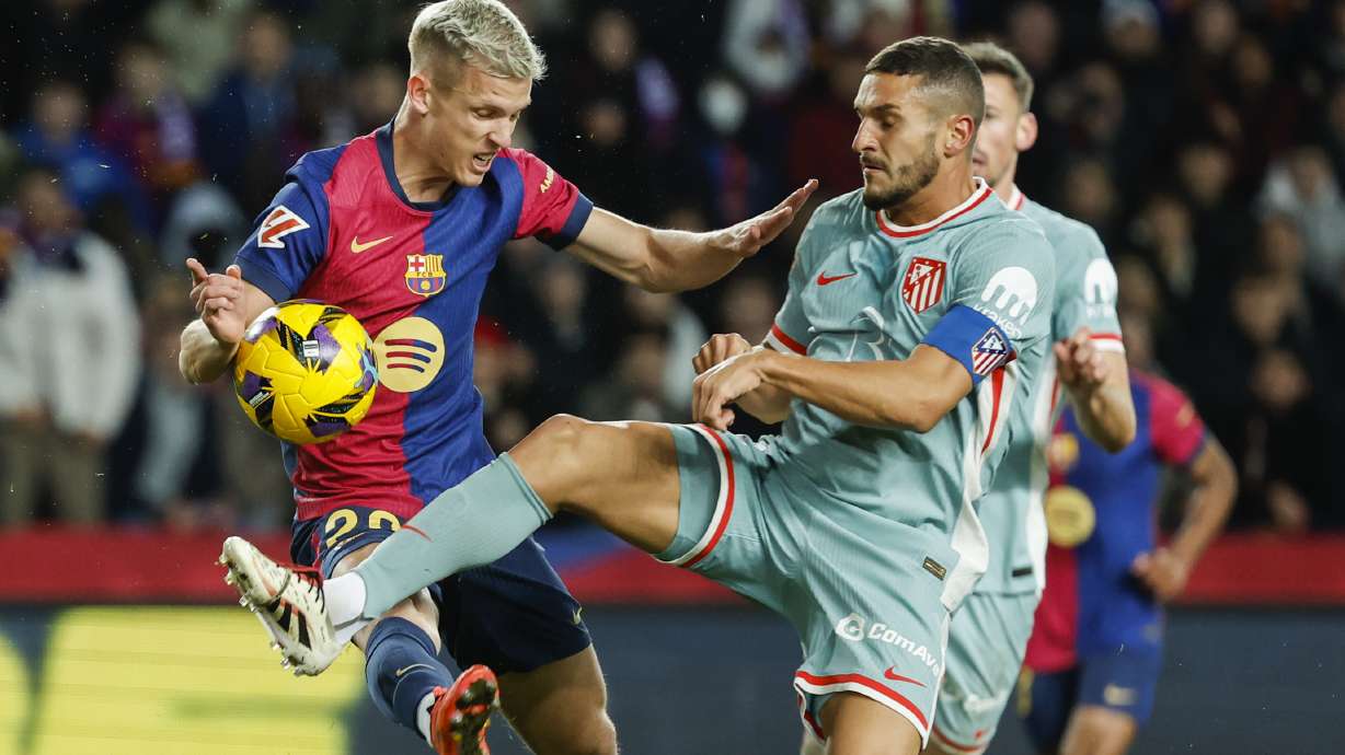 Barcelona's Dani Olmo, left, duels for the ball with Atletico Madrid's Koke during the Spanish La Liga soccer match between Barcelona and Atletico Madrid at the Lluis Companys Olympic Stadium in Barcelona, Spain, Saturday, Dec. 21, 2024.