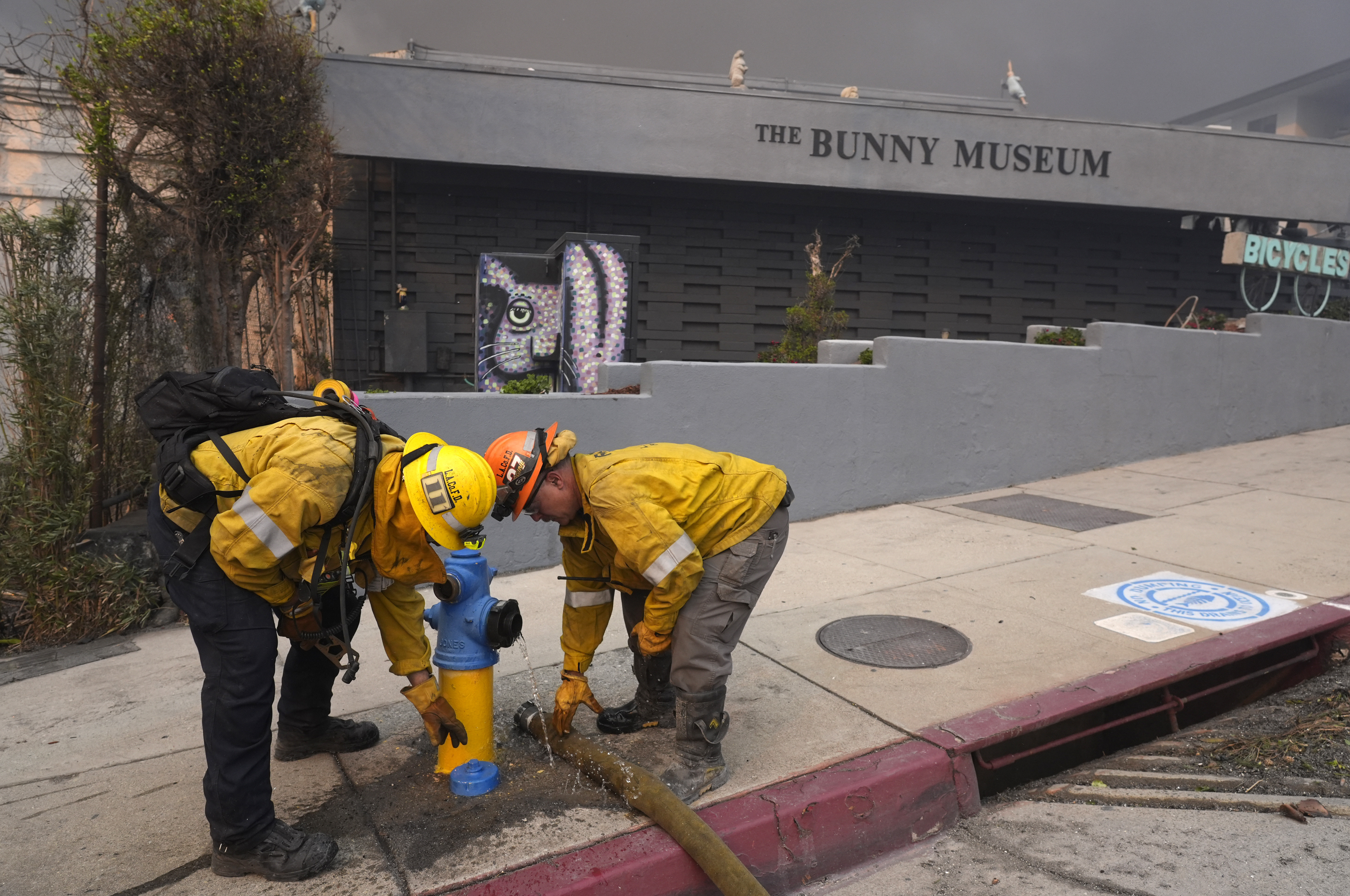Firefighters work a hydrant in front of the burning Bunny Museum, Wednesday in the Altadena section of Pasadena, Calif. Some Los Angeles fire hydrants have run dry as demand soared for water to quell wildfires.