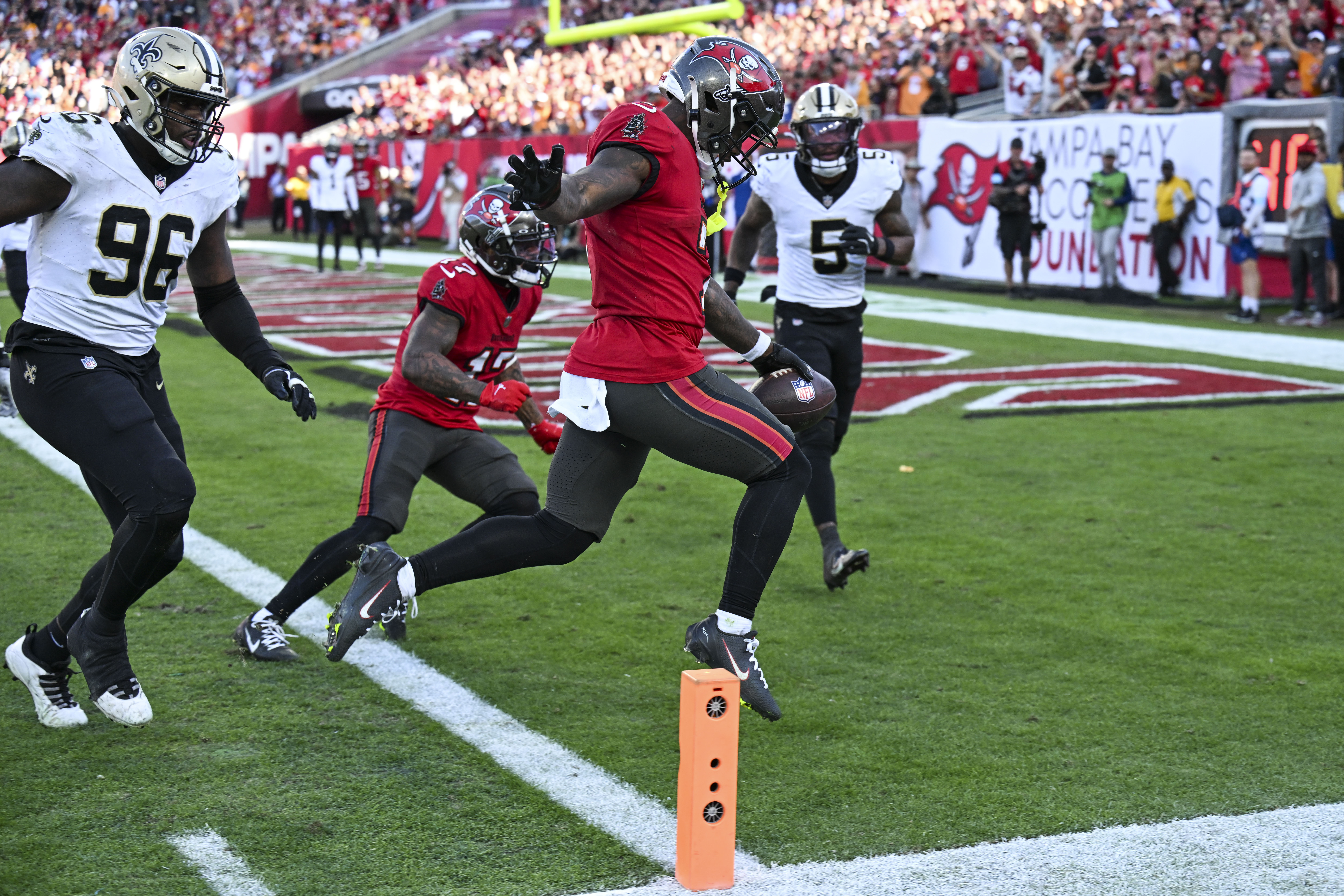 Tampa Bay Buccaneers running back Bucky Irving scores a touchdown between New Orleans Saints defensive end Carl Granderson (96) and cornerback Will Harris (5) during the second half of an NFL football game Sunday, Jan. 5, 2025, in Tampa, Fla. The Buccaneers won 27-19. 