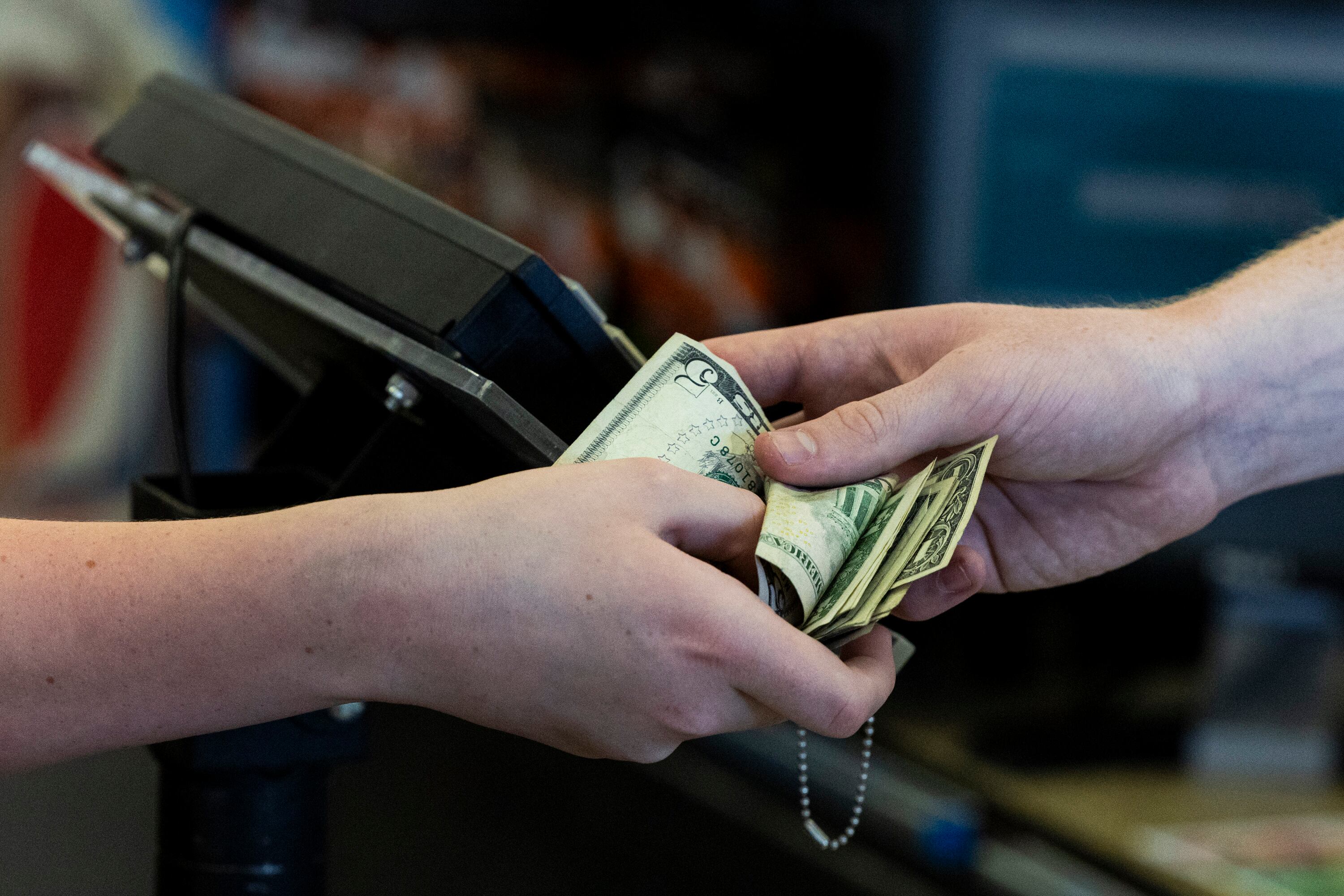 A customer pays using cash at Ream’s in Sandy on Aug. 13, 2024.