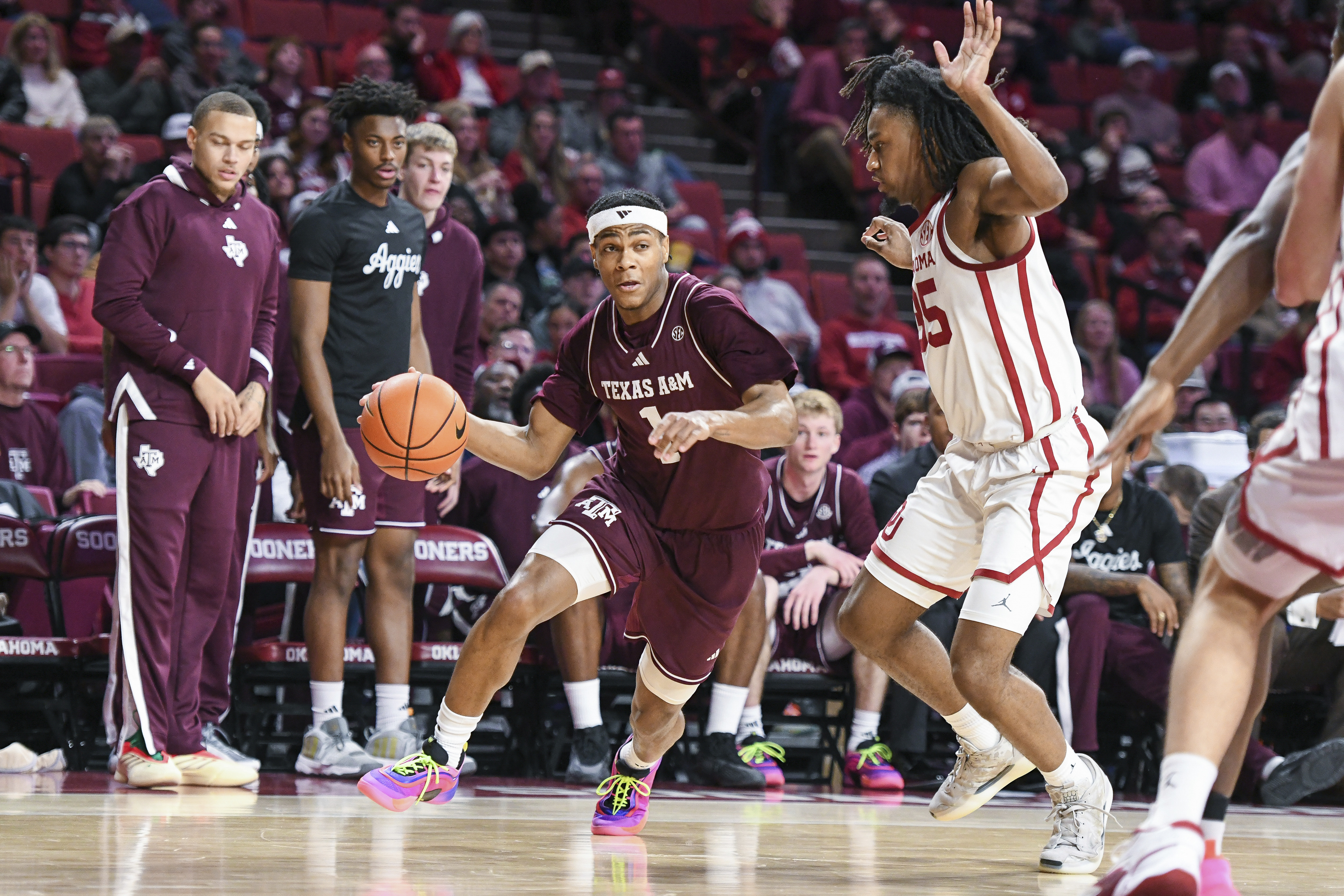 Texas A&M guard Zhuric Phelps, left, drives past Oklahoma forward Glenn Taylor Jr., right, during the second half of an NCAA college basketball game, Wednesday, Jan. 8, 2025, in Norman, Okla.