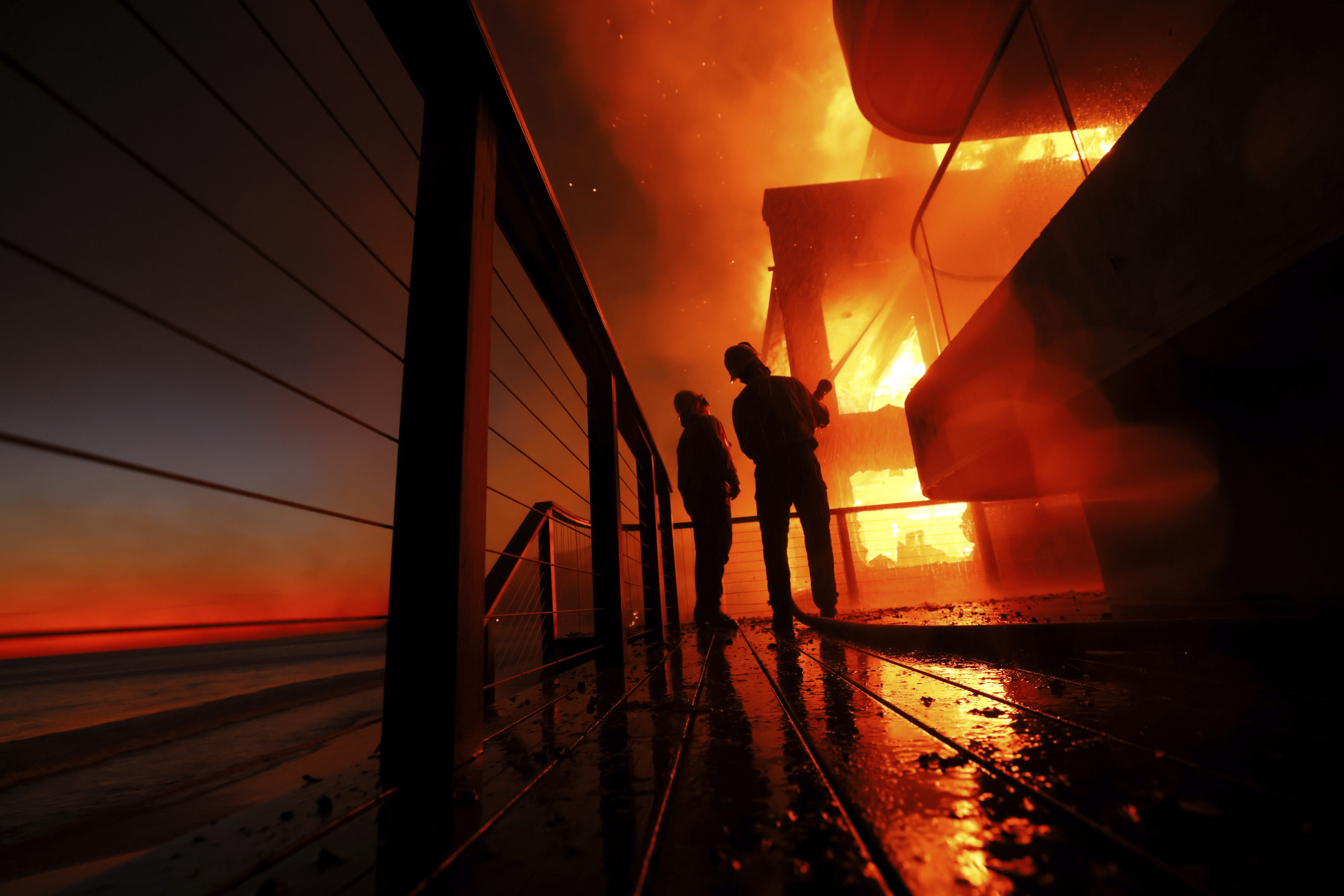 Firefighters battle devastating Los Angeles wildfires as winds calm somewhat