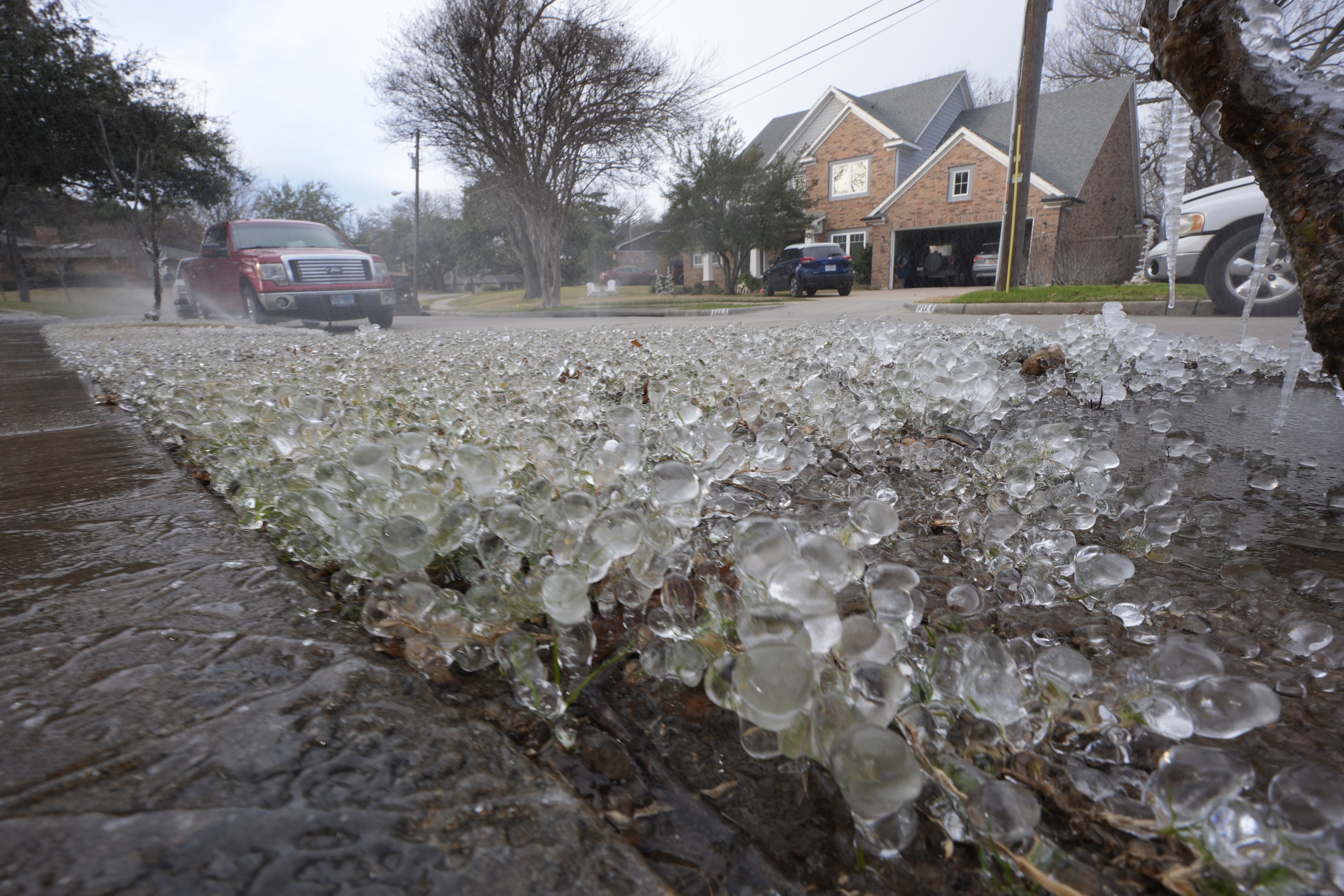 Cold temperatures and a lawn sprinkler create ice on grass ahead of a winter storm expected to hit the North Texas region later tomorrow Wednesday, in Richardson, Texas.
