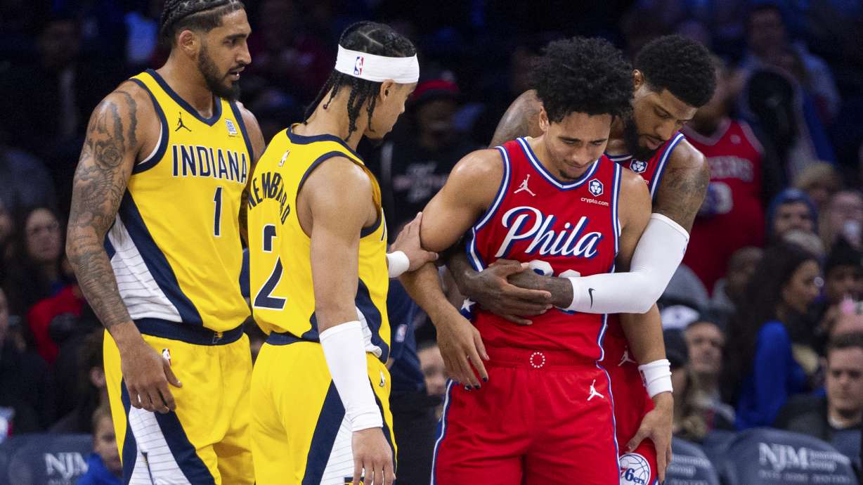 Philadelphia 76ers' Jared McCain, center right, gets helped by Paul George, right, and Indiana Pacers' Andrew Nembhard, center left, after a hard fall to the court during the first half of an NBA basketball game, Friday, Dec. 13, 2024, in Philadelphia.