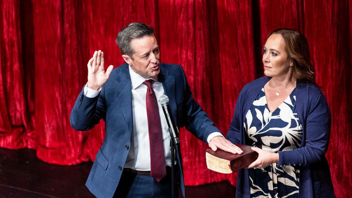 Attorney General Derek Brown holds his hand on a Bible held by his wife, Emilie Brown, as he takes the oath of office at the Eccles Theater in Salt Lake City on Wednesday.