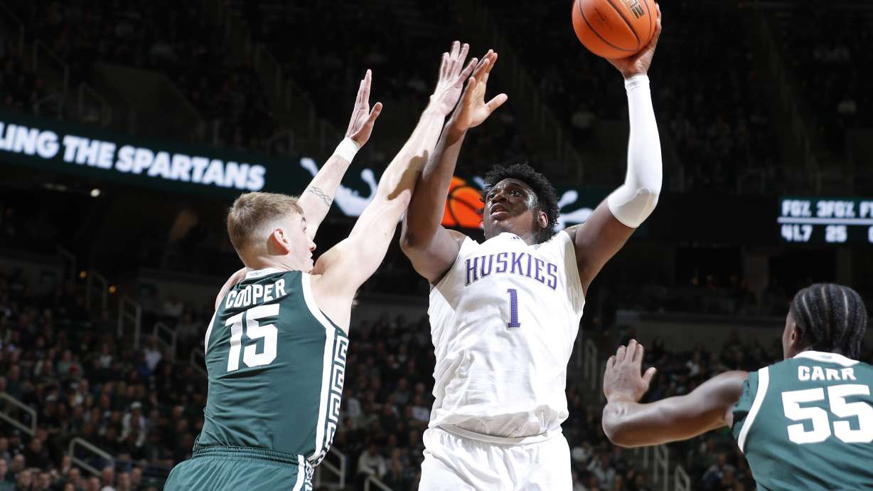 Washington forward Great Osobor (1) shoots against Michigan State center Carson Cooper (15), left, and Michigan State forward Coen Carr (55) during the first half of an NCAA college basketball game, Thursday, Jan. 9, 2025, in East Lansing, Mich.