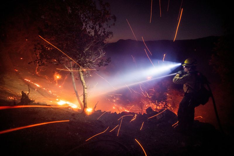 The wind whips embers while a firefighter battles the fire in the Angeles National Forest near Mt. Wilson as the wildfires burn in the Los Angeles area, during the Eaton Fire in Altadena, California, on Thursday.