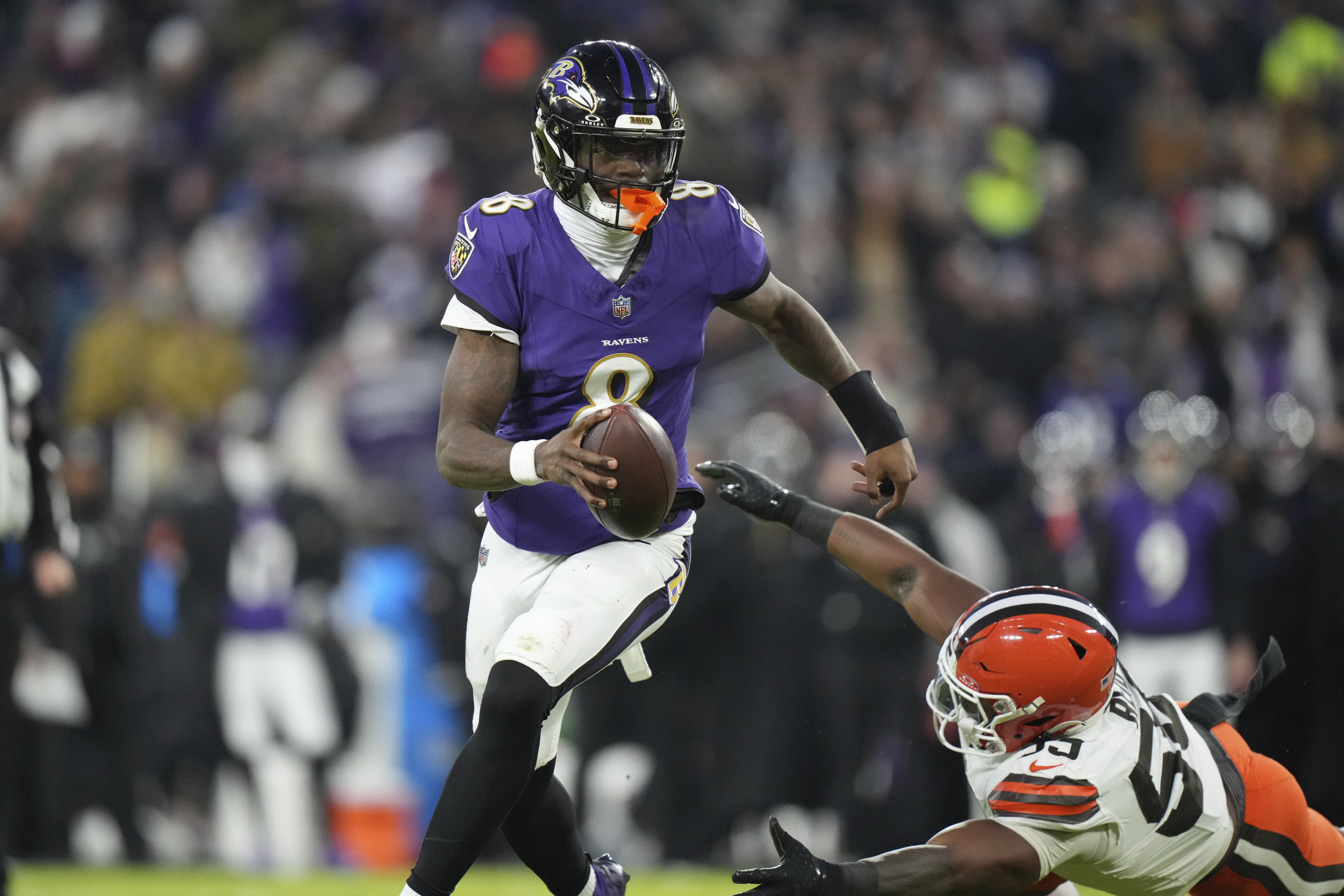 Baltimore Ravens quarterback Lamar Jackson (8) runs past Cleveland Browns linebacker Winston Reid, right, during the first half of an NFL football game Saturday, Jan. 4, 2025, in Baltimore.