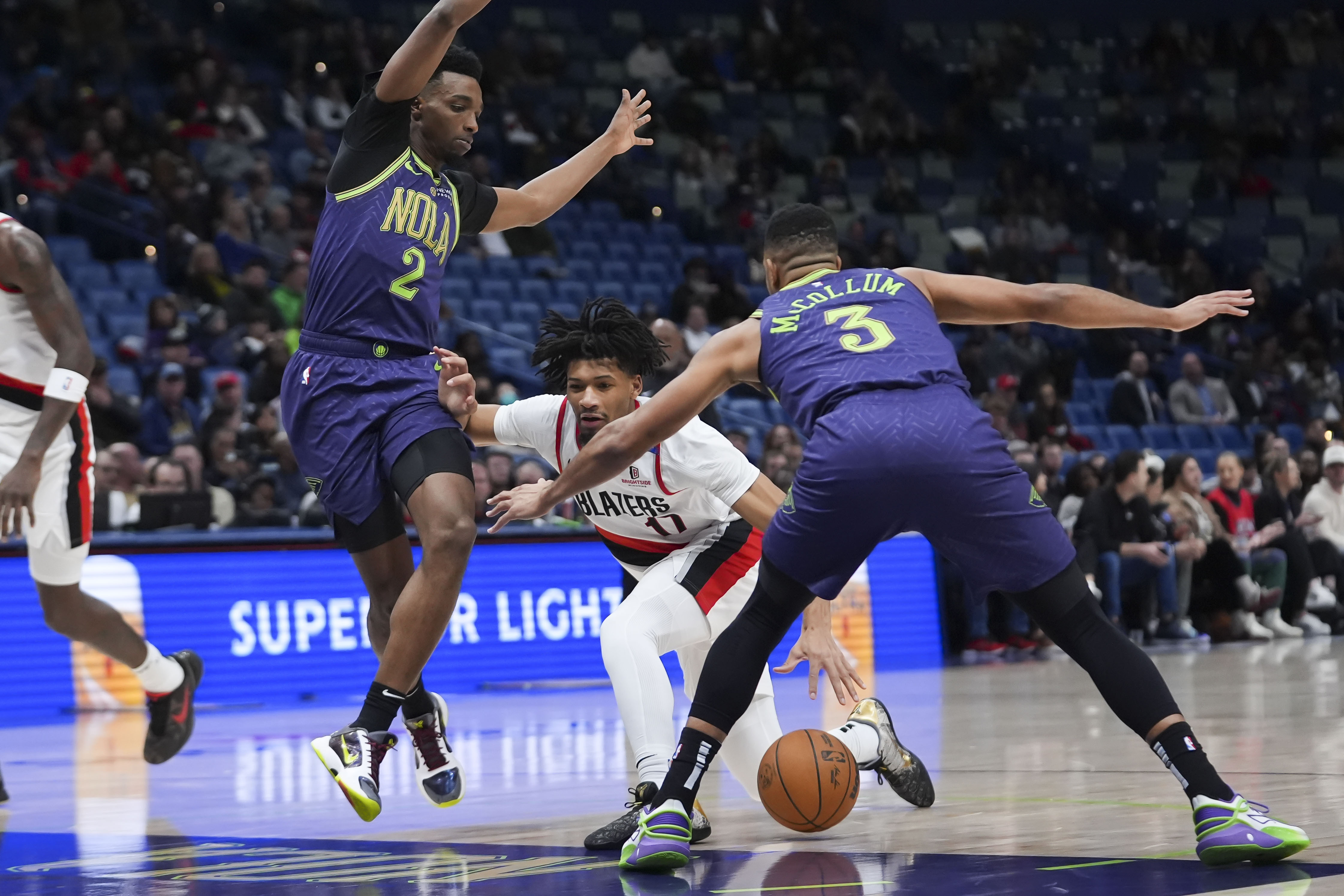 Portland Trail Blazers guard Shaedon Sharpe (17) drives to the basket between New Orleans Pelicans forward Herbert Jones (2) and guard CJ McCollum (3) in the first half of an NBA basketball game in New Orleans, Wednesday, Jan. 8, 2025.