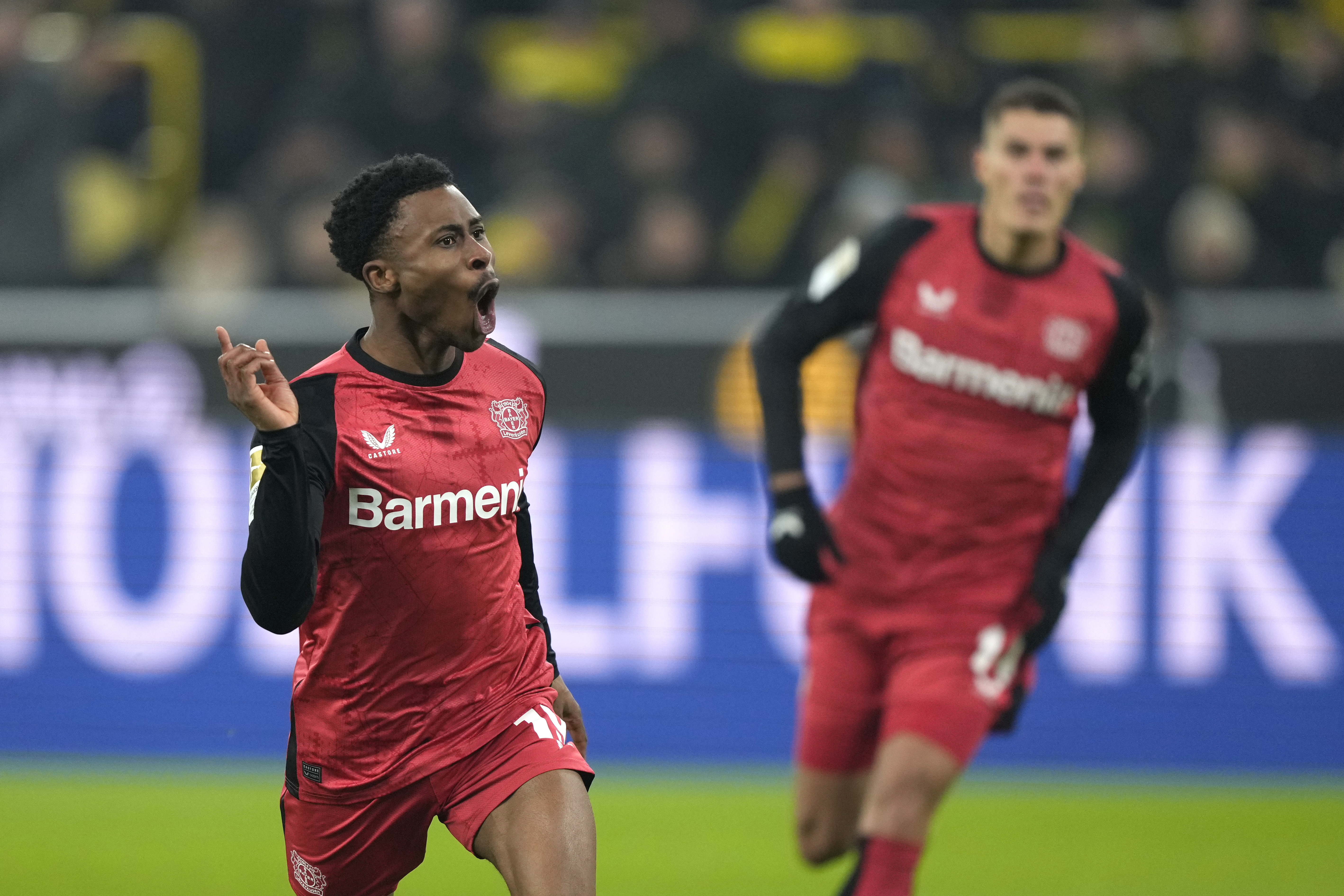 Leverkusen's Nathan Tella, left, celebrates after scoring his side's opening goal during the German Bundesliga soccer match between Borussia Dortmund and Bayer Leverkusen at the Signal-Iduna Park in Dortmund, Germany, Friday, Jan. 10, 2025.
