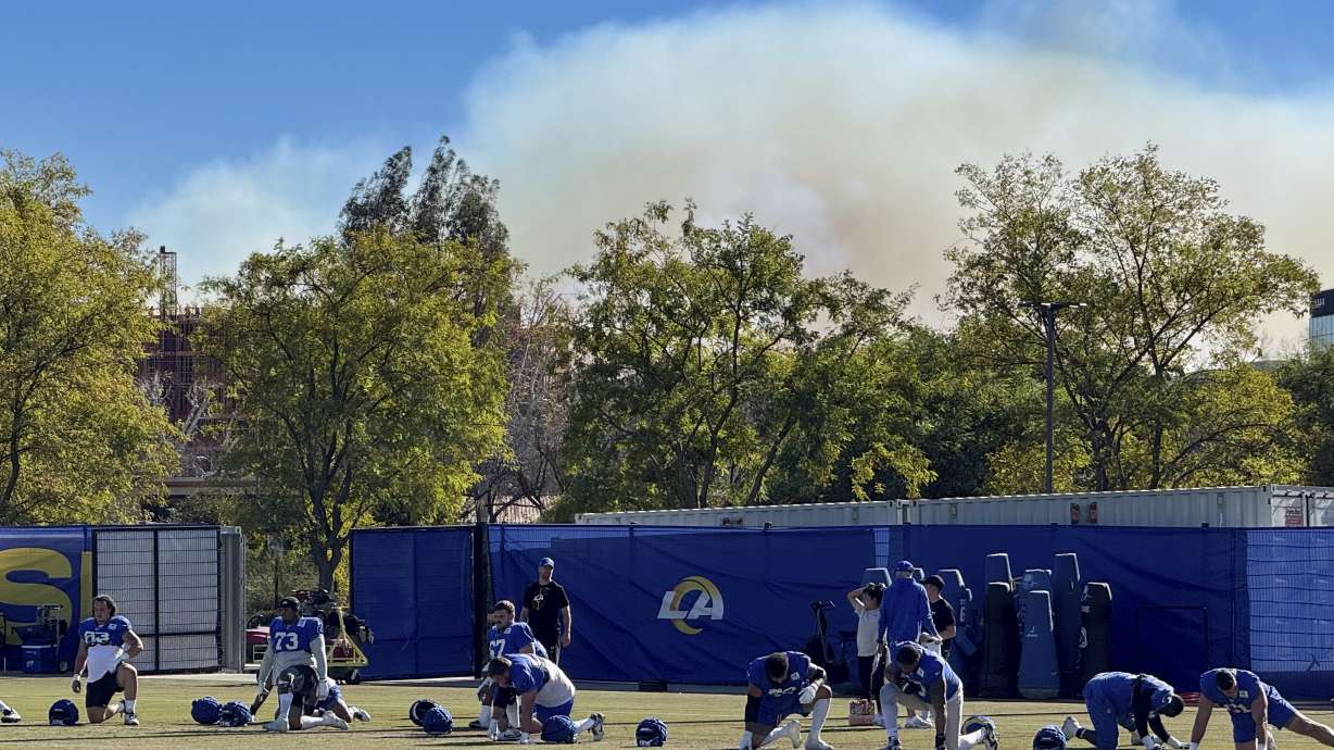 The Los Angeles Rams NFL football team practices under a plume of smoke from the Palisades Fire in preparation for a playoff game against the Minnesota Vikings in the Woodland Hills section of Los Angeles, Friday, Jan. 10, 2025.