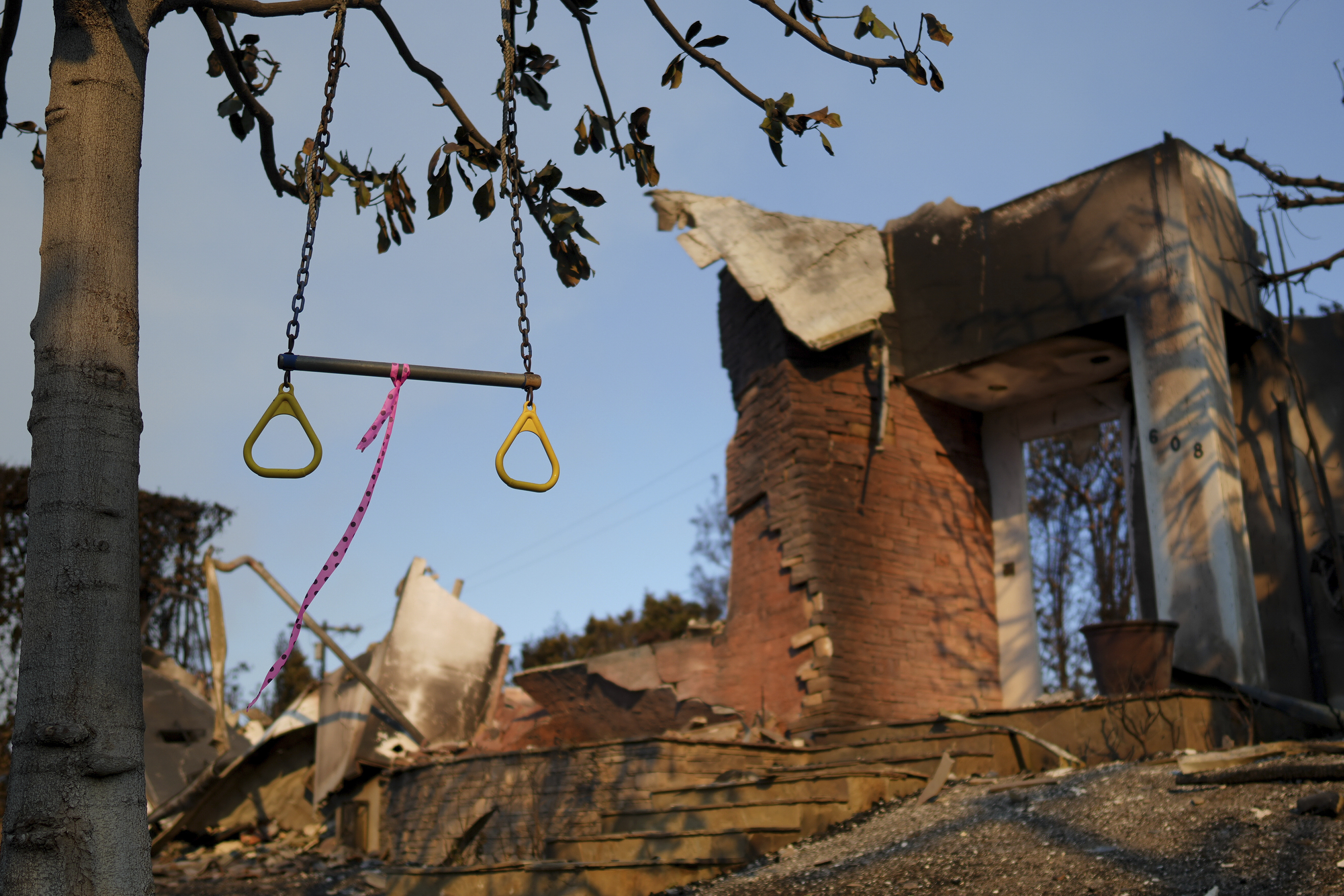 A swing hangs from a tree in front of a fire-damaged residence in the aftermath of the Palisades Fire in the Pacific Palisades neighborhood of Los Angeles, Friday, Jan. 10, 2025.