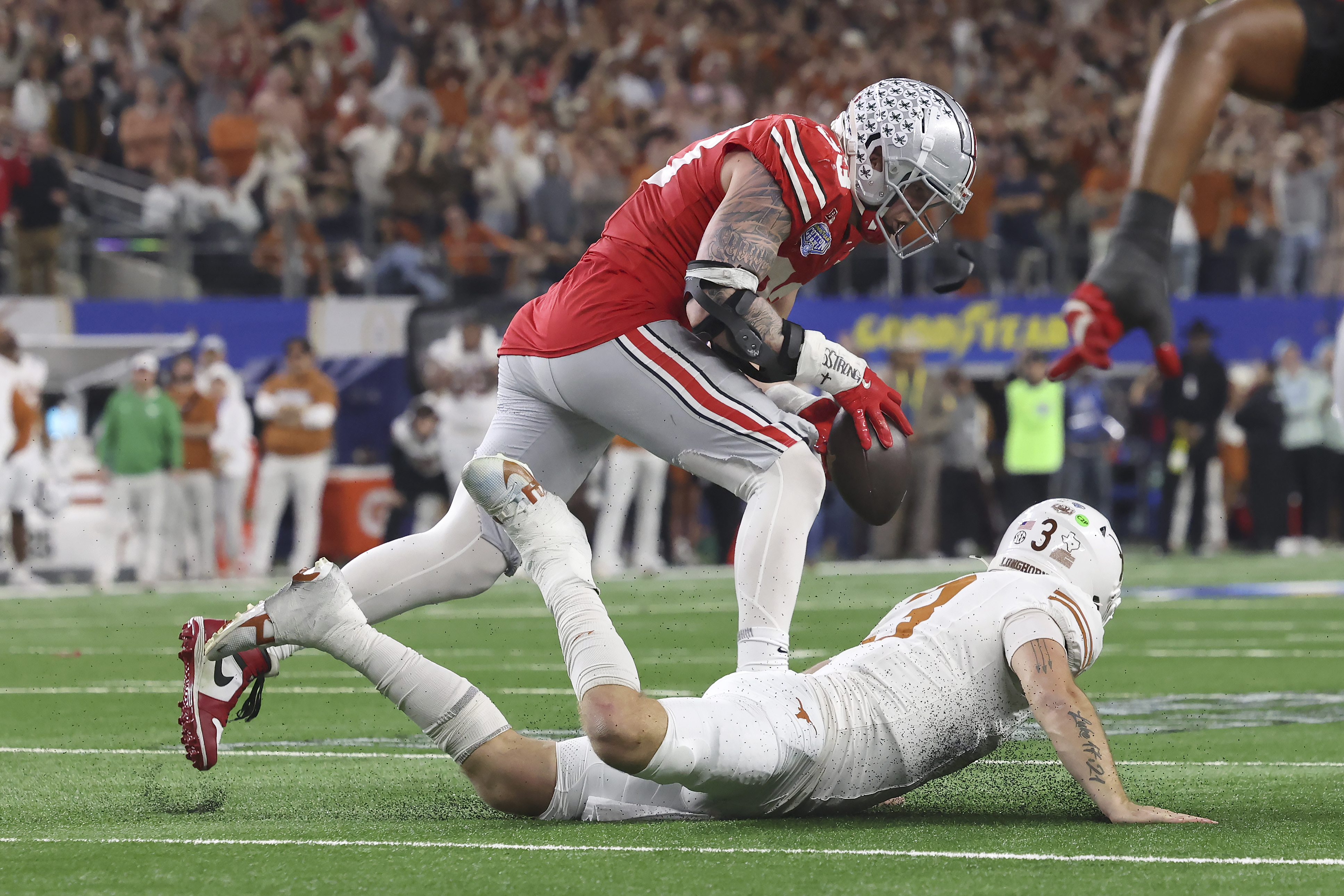 Ohio State defensive end Jack Sawyer, top, runs for a touchdown after recovering a fumble by Texas quarterback Quinn Ewers, bottom, during the second half of the Cotton Bowl College Football Playoff semifinal game, Friday, Jan. 10, 2025, in Arlington, Texas.