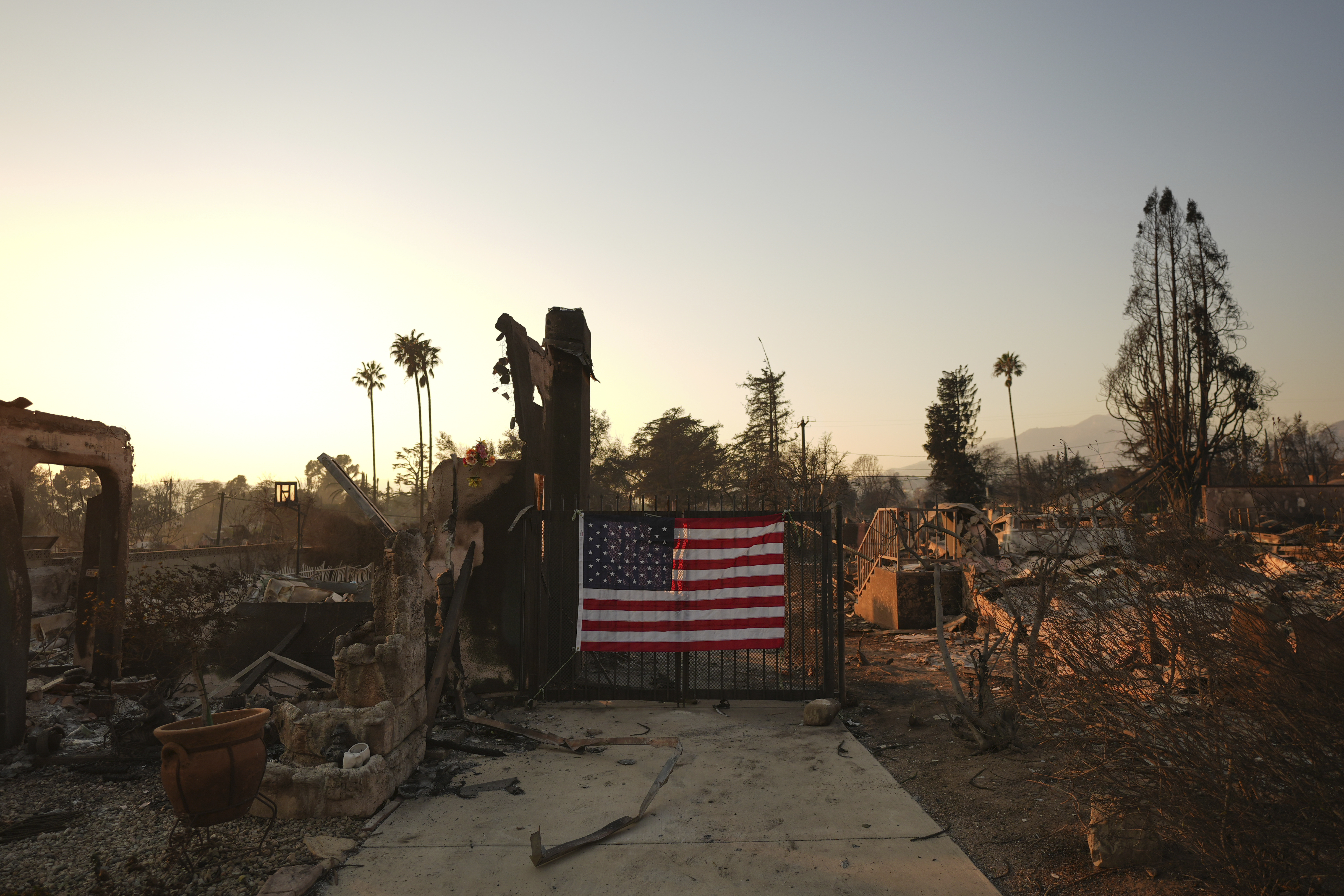 An American flag hangs on the gate of a home destroyed by the Eaton Fire in Altadena, Calif., Friday, Jan. 10, 2025.