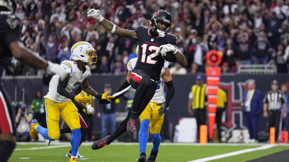 Houston Texans wide receiver Nico Collins (12) leaps into the end zone for a touchdown after catching a pass as Los Angeles Chargers' Kristian Fulton (7) defends during the first half of an NFL wild-card playoff football game Saturday, Jan. 11, 2025, in Houston.