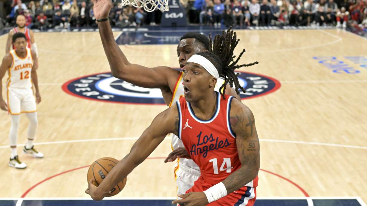 Los Angeles Clippers guard Terance Mann (14) makes a pass around Atlanta Hawks forward Onyeka Okongwu during the second half of an NBA basketball game Saturday, Jan. 4, 2025, in Los Angeles.