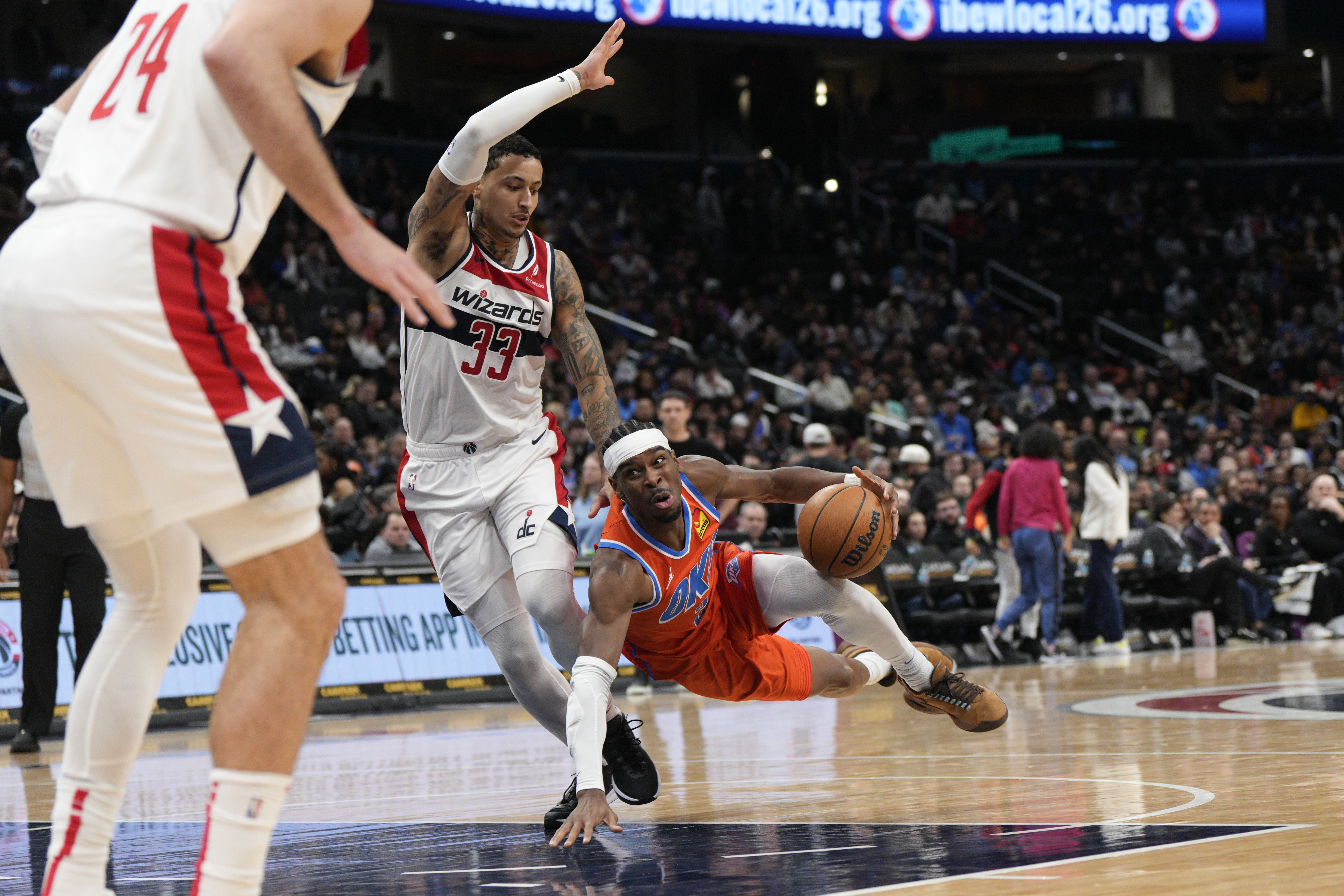 Oklahoma City Thunder guard Shai Gilgeous-Alexander, right, falls after being fouled by Washington Wizards forward Kyle Kuzma (33) during the first half of an NBA basketball game Sunday, Jan. 12, 2025, in Washington.