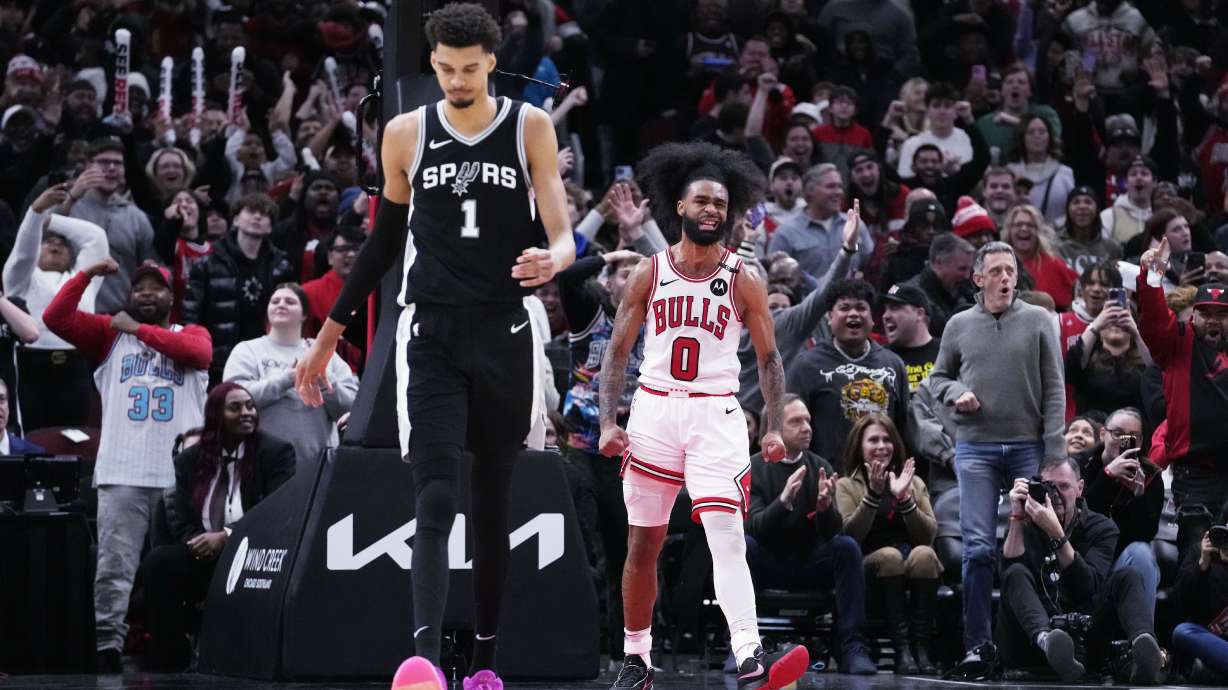 Chicago Bulls guard Coby White (0) reacts after dunking as San Antonio Spurs center Victor Wembanyama (1) walks on the court during the second half of an NBA basketball game in Chicago, Monday, Jan. 6, 2025.
