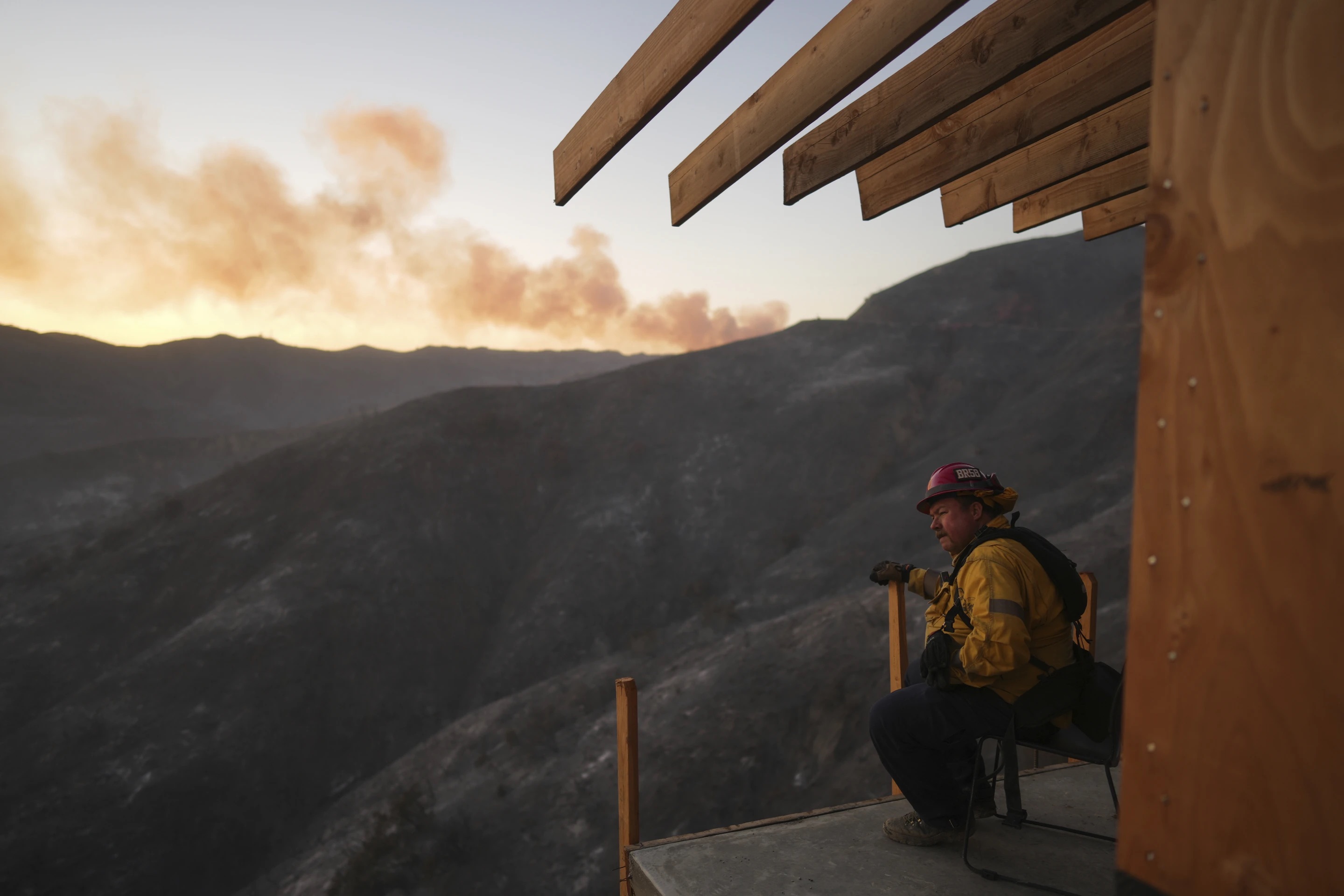 A firefighter rests as crews battle the Palisades Fire in Mandeville Canyon, Saturday, in Los Angeles.