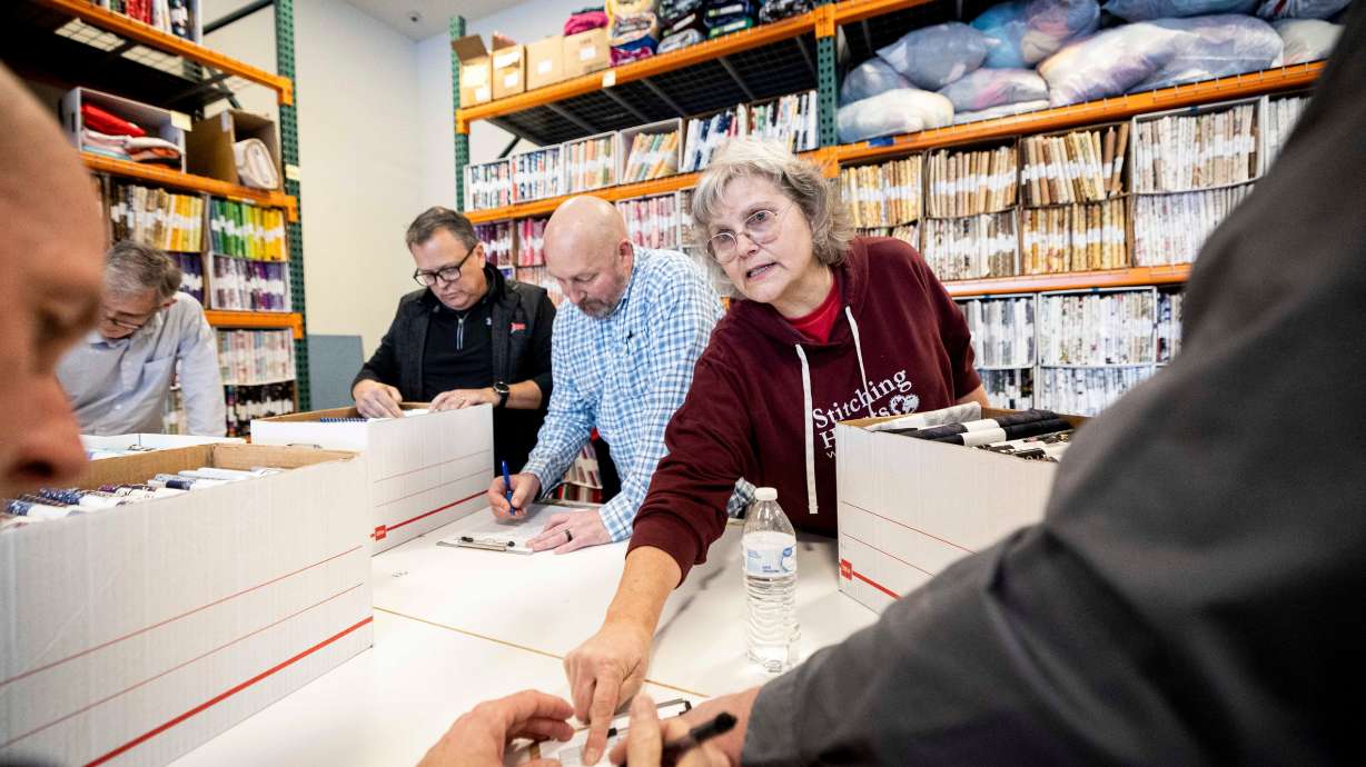 Krysti Wright, executive director of Stitching Hearts Worldwide, helps volunteers from Asphalt Zipper catalogue fabrics at Stitching Hearts Worldwide’s headquarters in Pleasant Grove on Jan. 7.