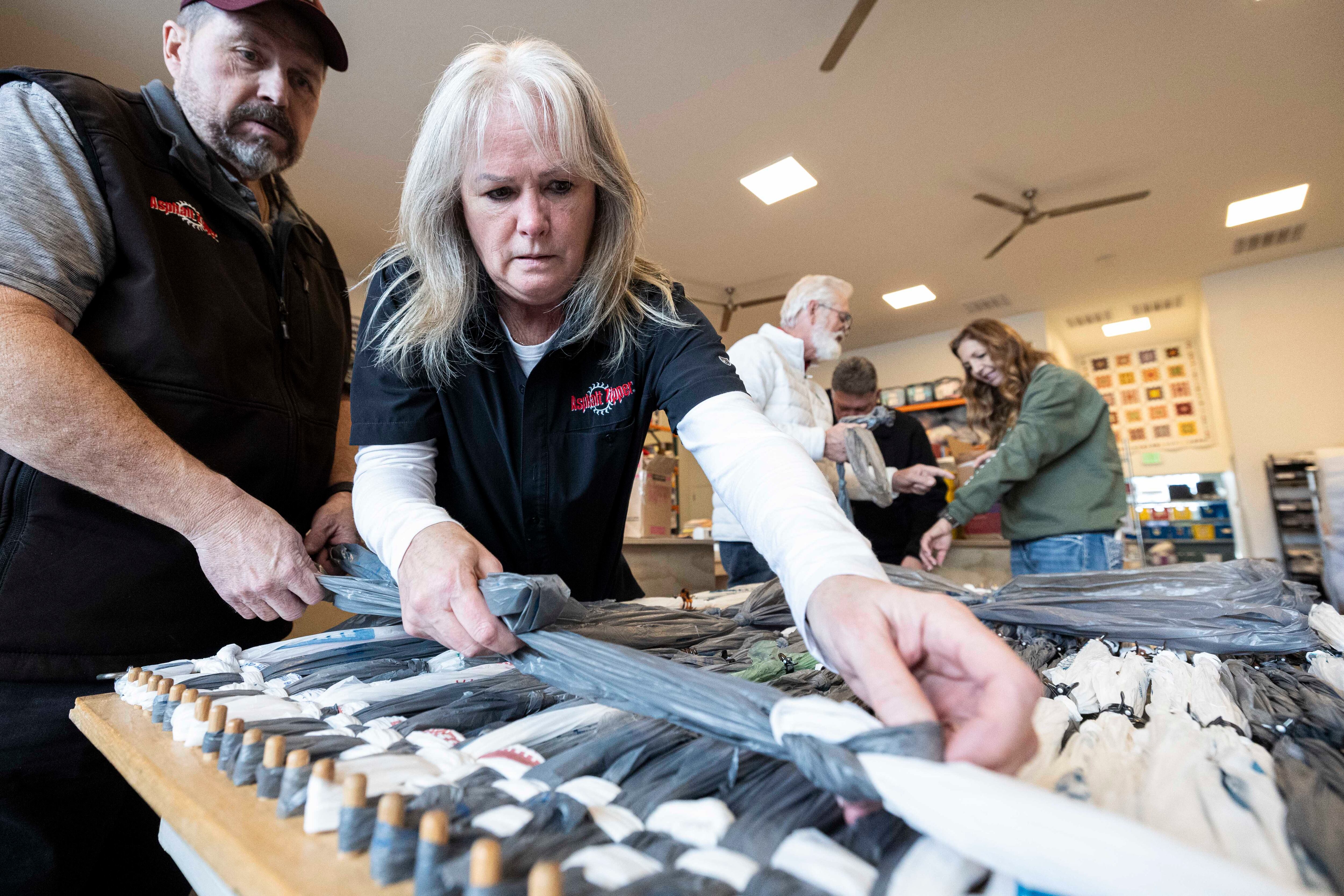 Karen Baker and Shane Beck, both volunteers from Asphalt Zipper, work on weaving together a plastic bag mat at Stitching Hearts Worldwide’s headquarters in Pleasant Grove on Jan. 7.